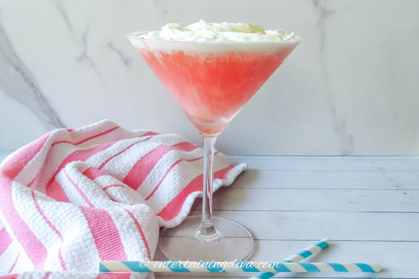 Side view of a guava martini topped with whipped cream