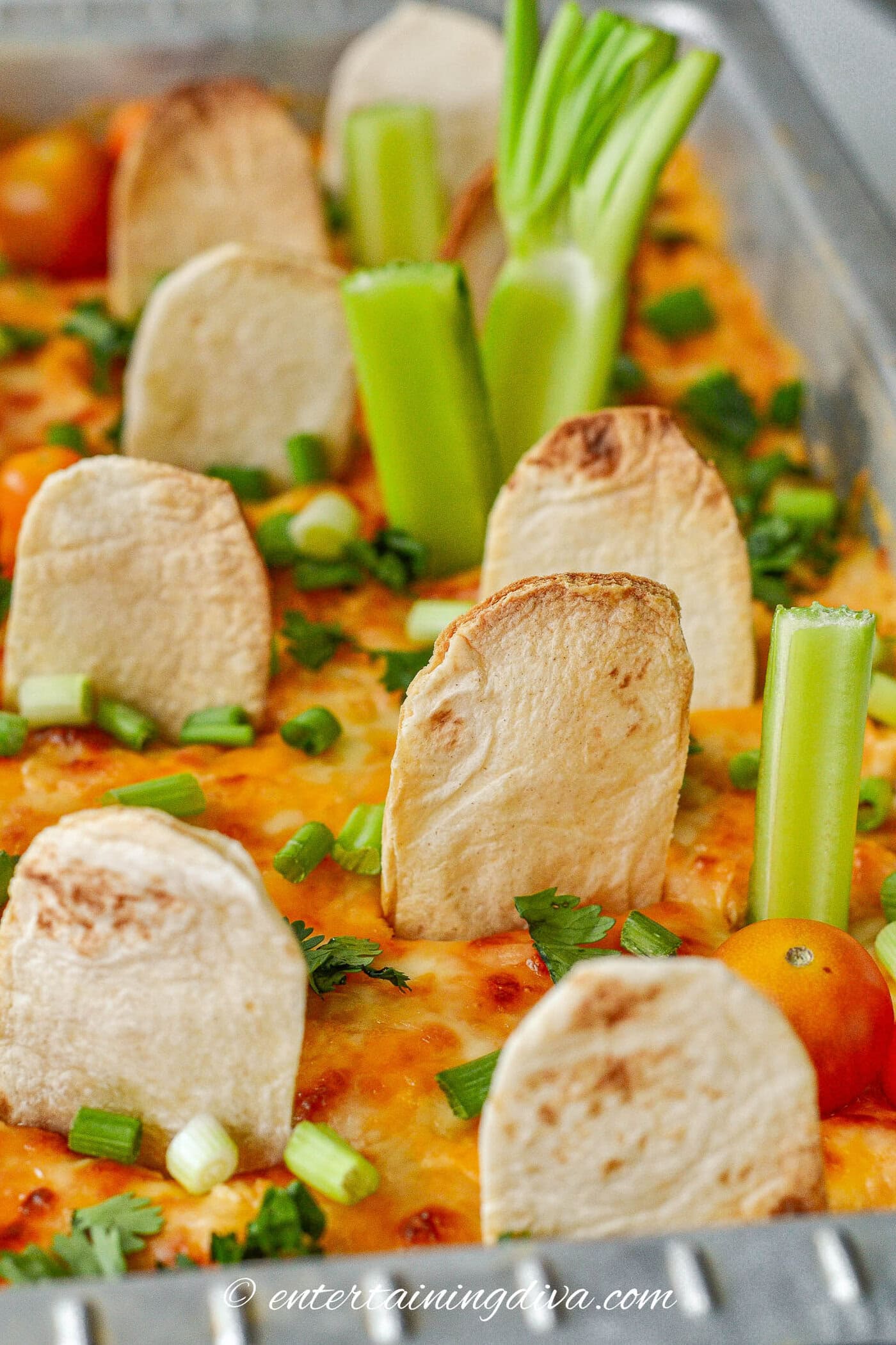 Halloween buffalo chicken dip decorated with celery "trees", tortilla gravestones and tomato "pumpkins"
