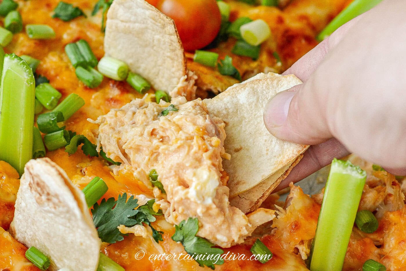 A tombstone tortilla being dipped into Halloween buffalo chicken dip