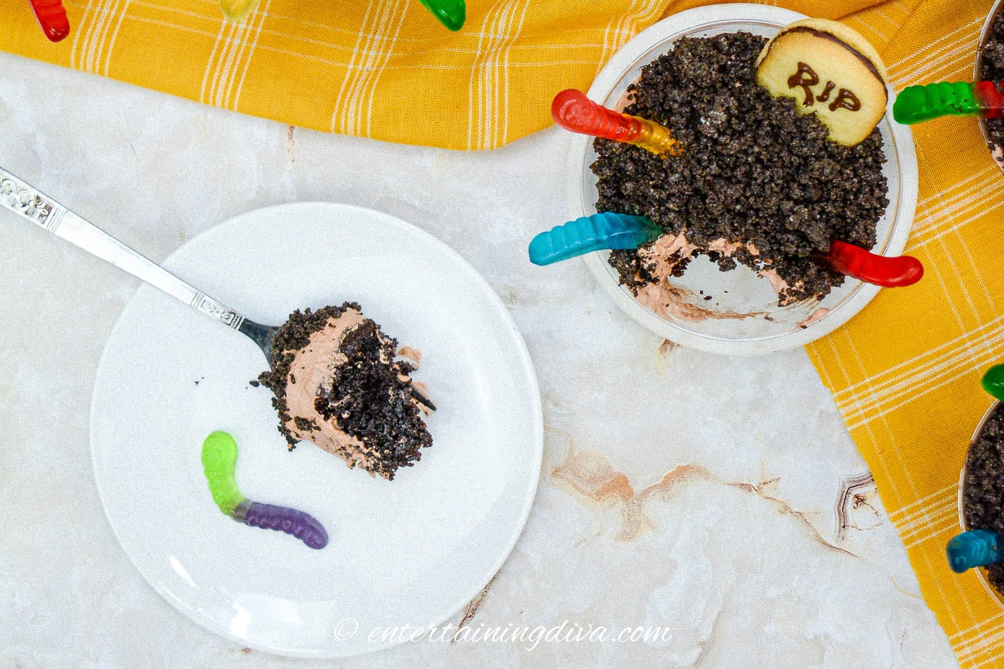A plate with a forkful of chocolate cake beside a Halloween graveyard dirt pudding cup