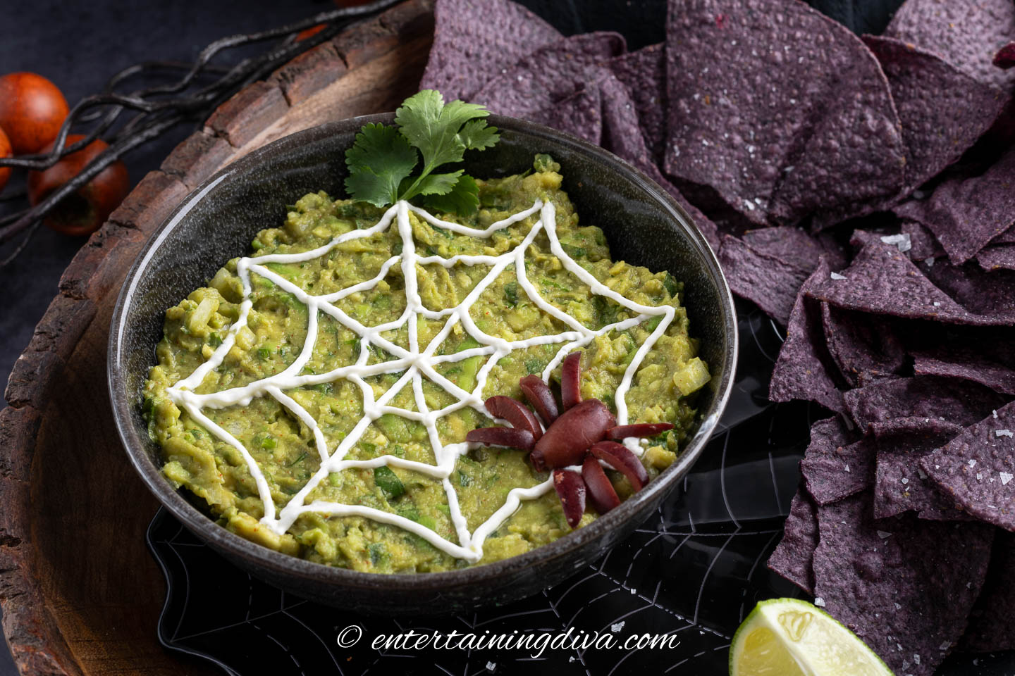 A bowl of Halloween guacamole on a table with blue corn chips