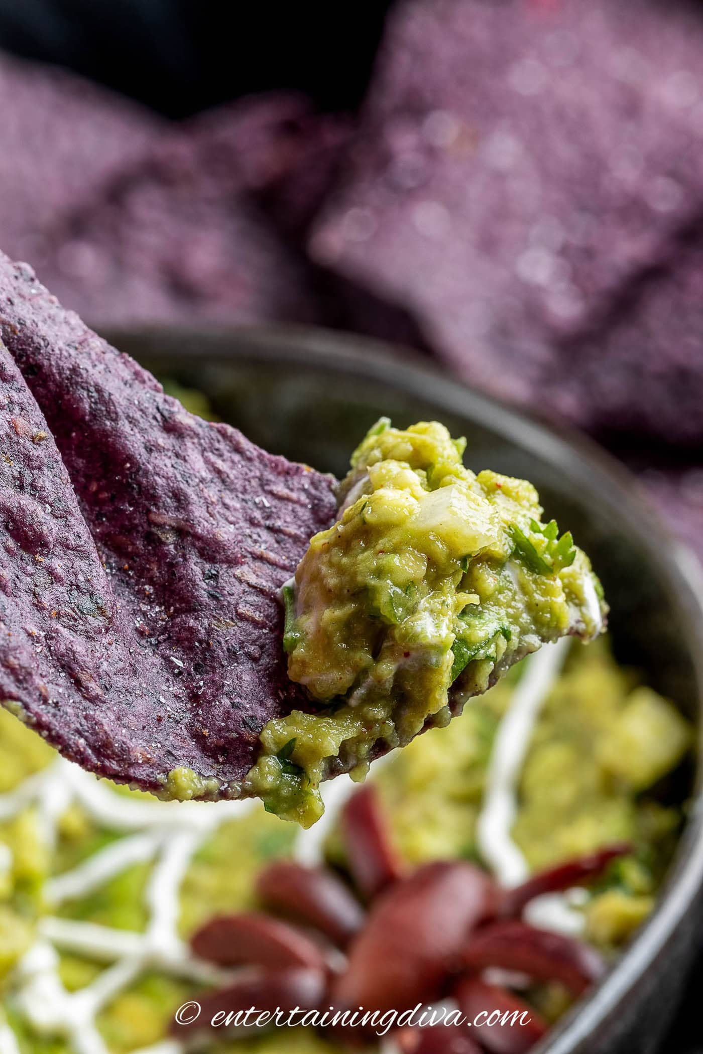 A close up of guacamole on a blue corn chip