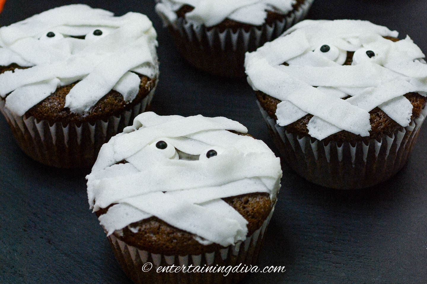 Mummy cupcakes on a black background.