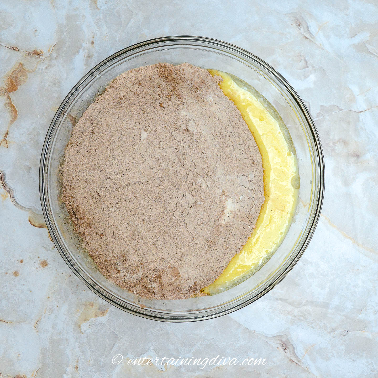 A bowl with a mixture of dry and wet chocolate cupcake ingredients.