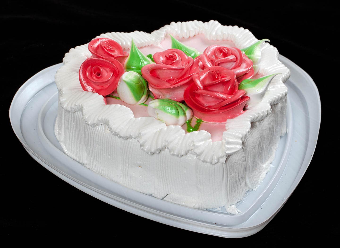 White heart cake with red roses and green leaves made with frosting