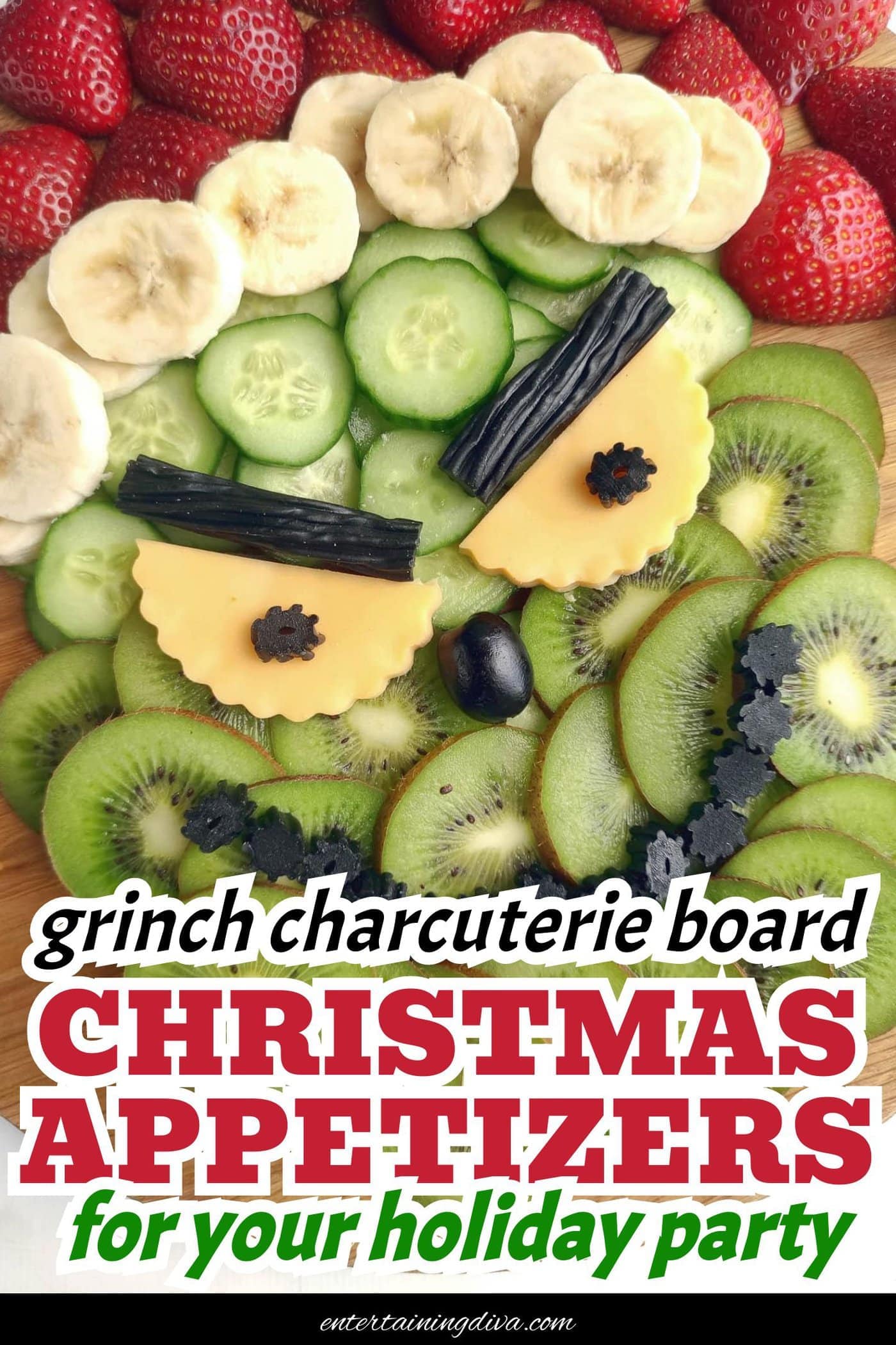 A platter arranged with strawberries, banana slices, cucumber, kiwi, cheese, black olives, and black licorice to resemble a smiling face on a wooden board.