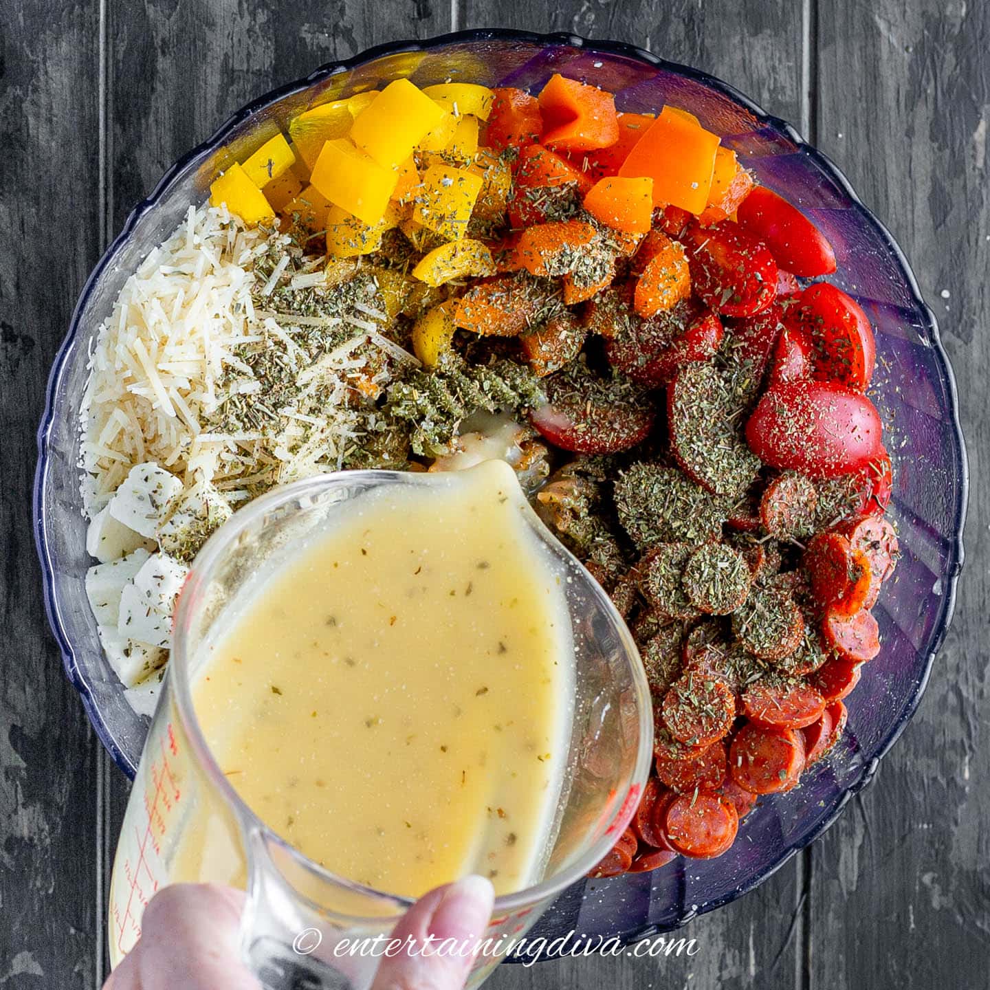 Italian salad dressing being poured over Italian pasta salad
