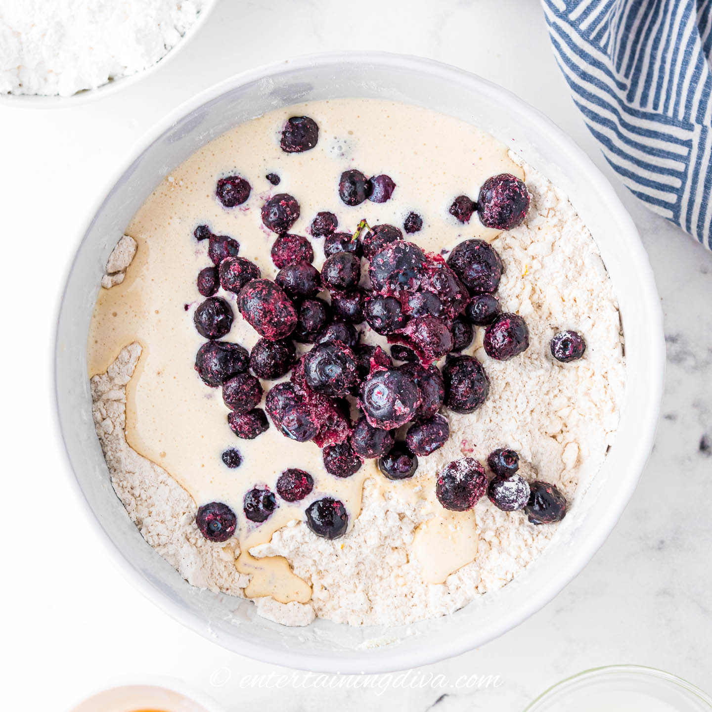scone wet and dry ingredients in a bowl with frozen blueberries