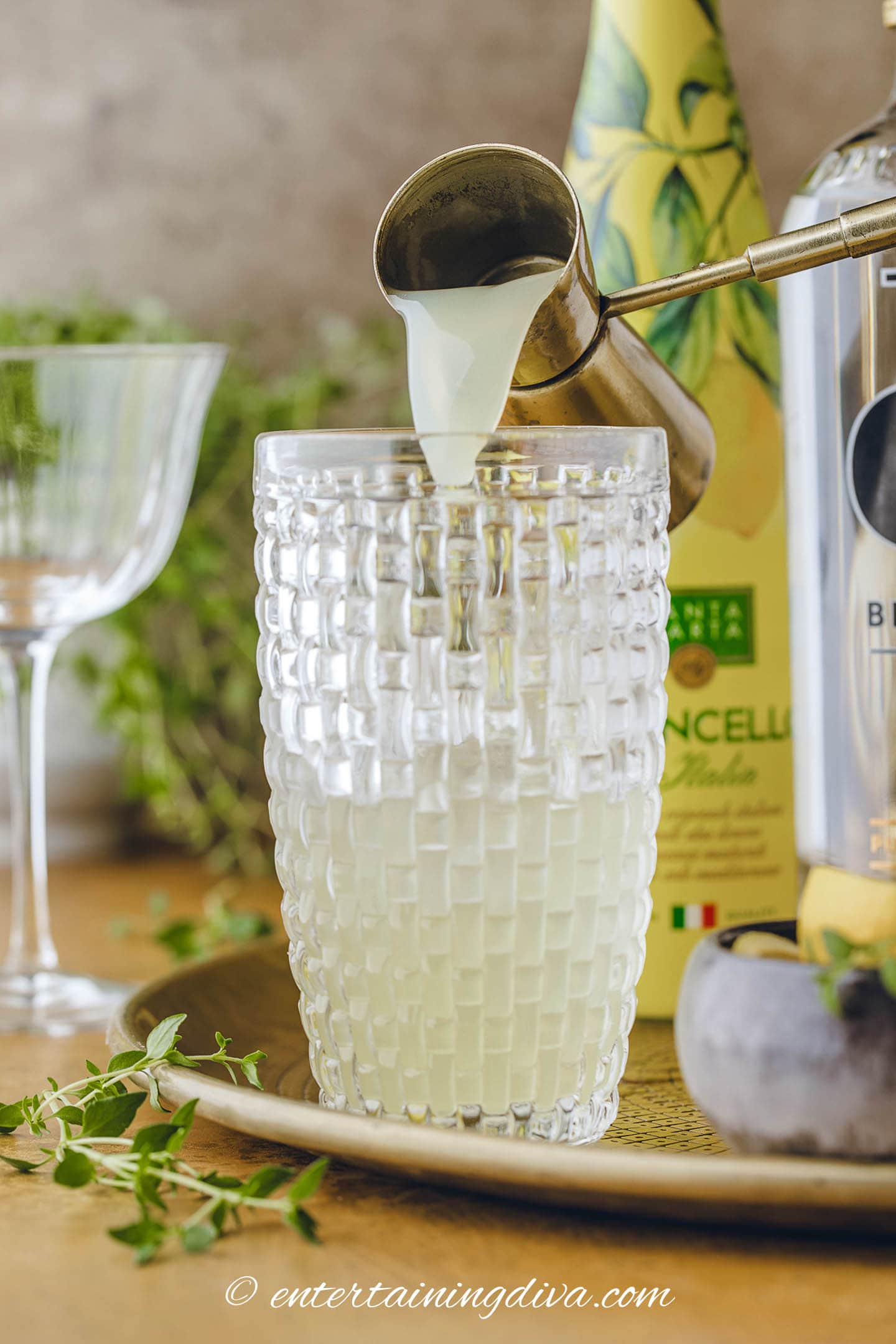 Lemon juice being poured into a cocktail shaker with vodka and limoncello