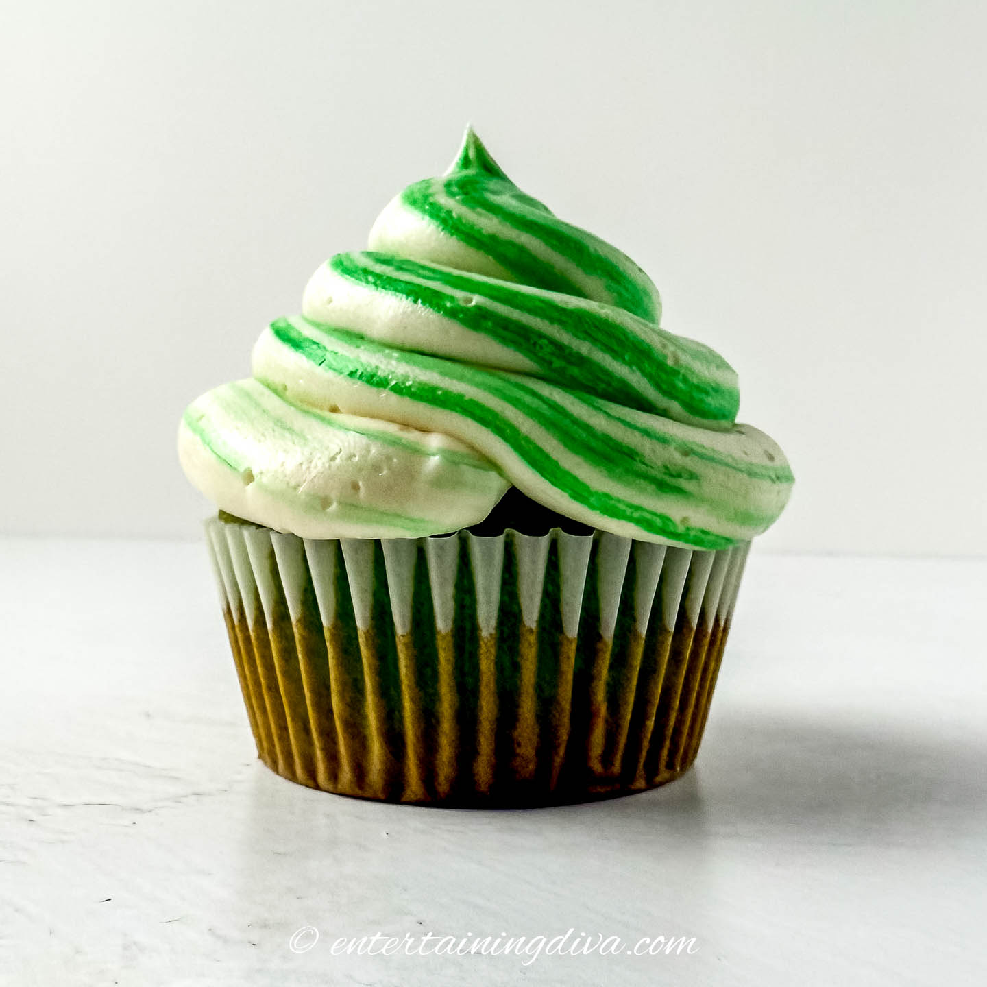 a cupcake with green and white striped buttercream frosting