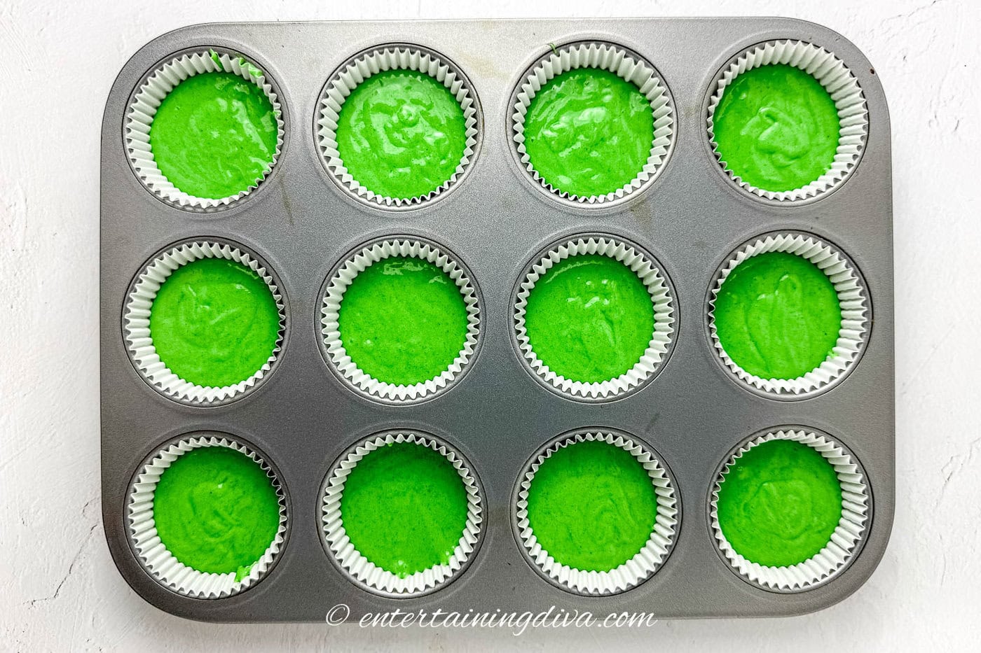green cupcake batter in a cupcake tin