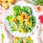 Mandarin orange romaine salad with vinaigrette dressing being served on a white plate