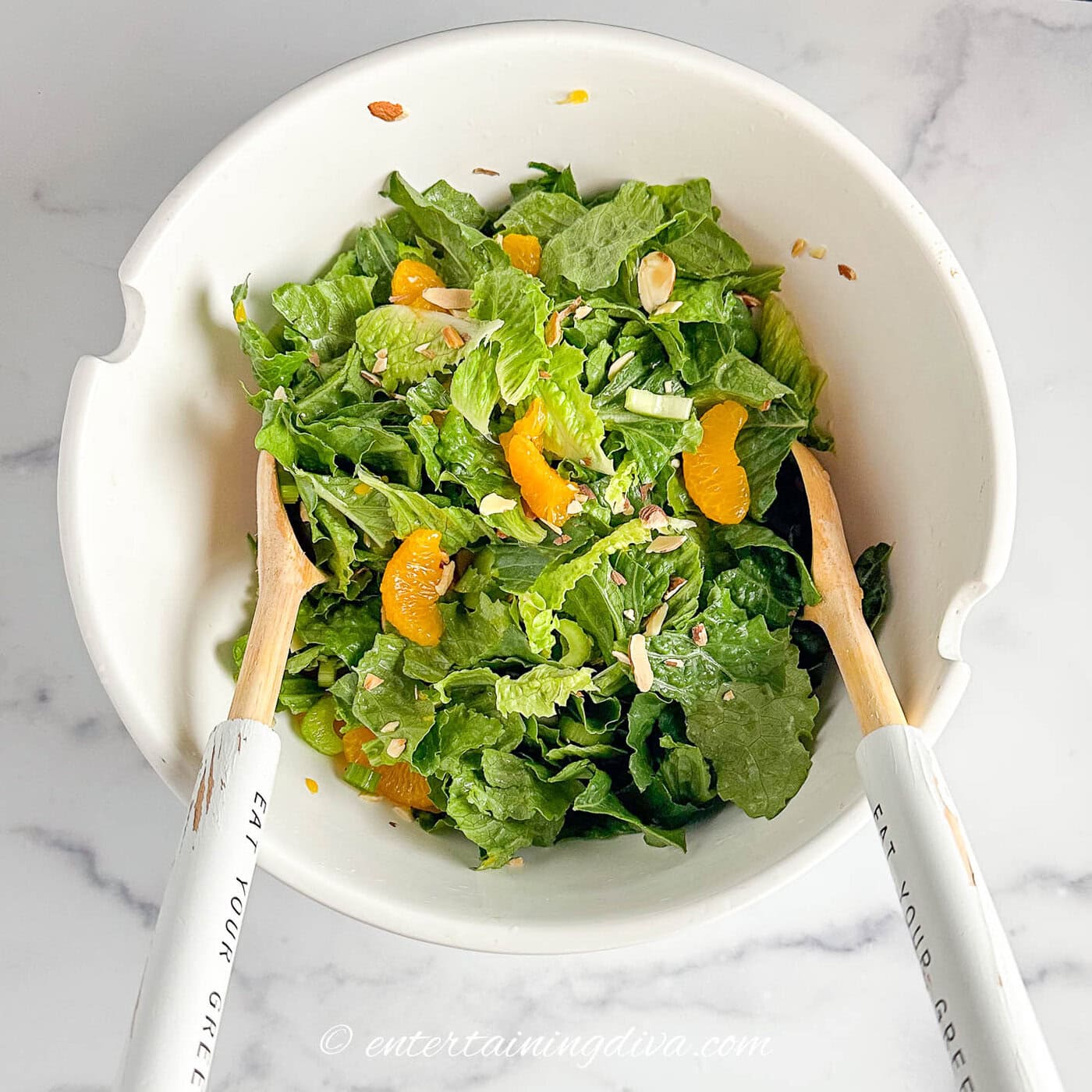 mandarin orange romaine salad being mixed in a bowl