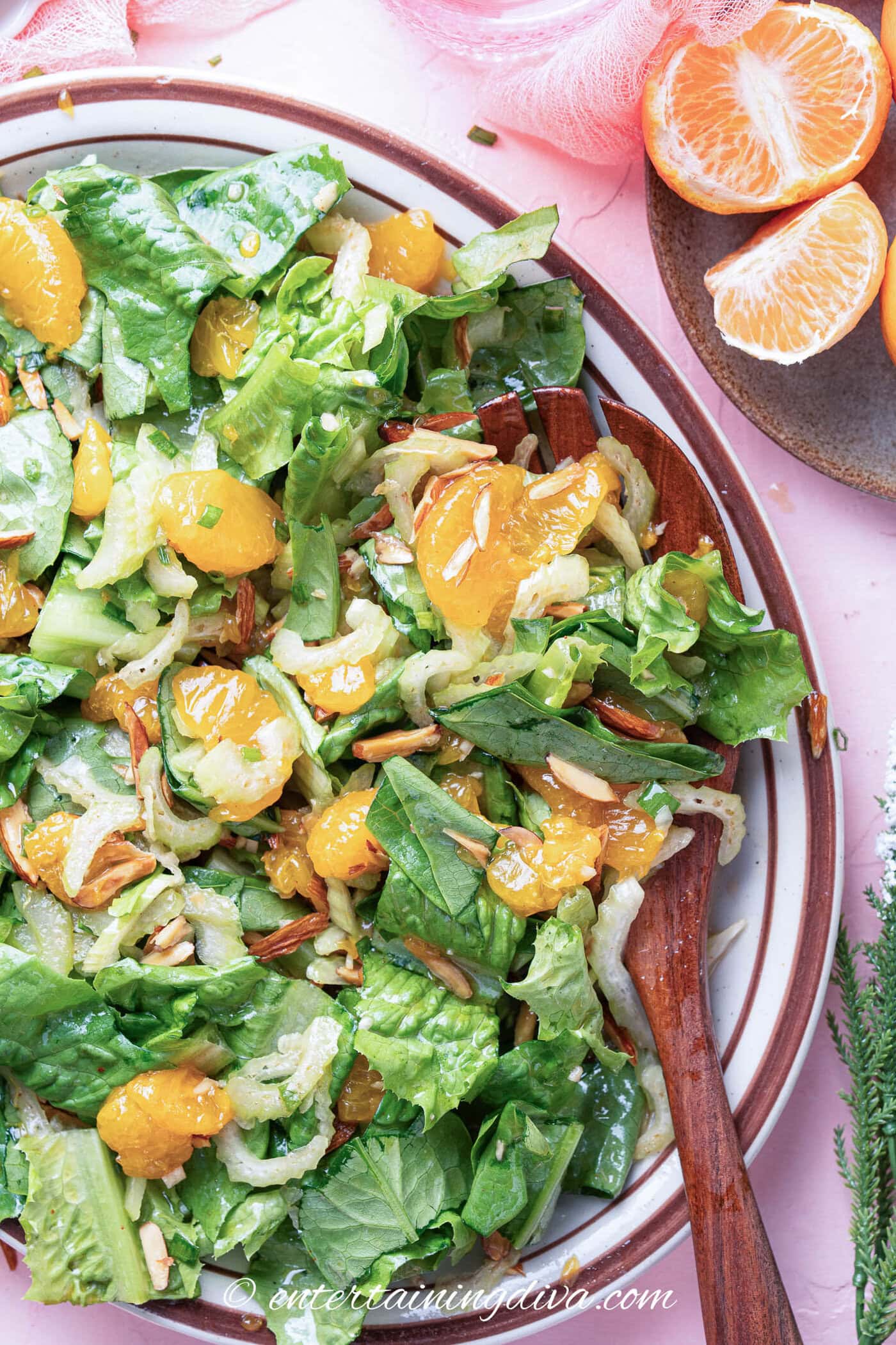 overhead view of mandarin orange romaine salad in a bowl with a serving spoon