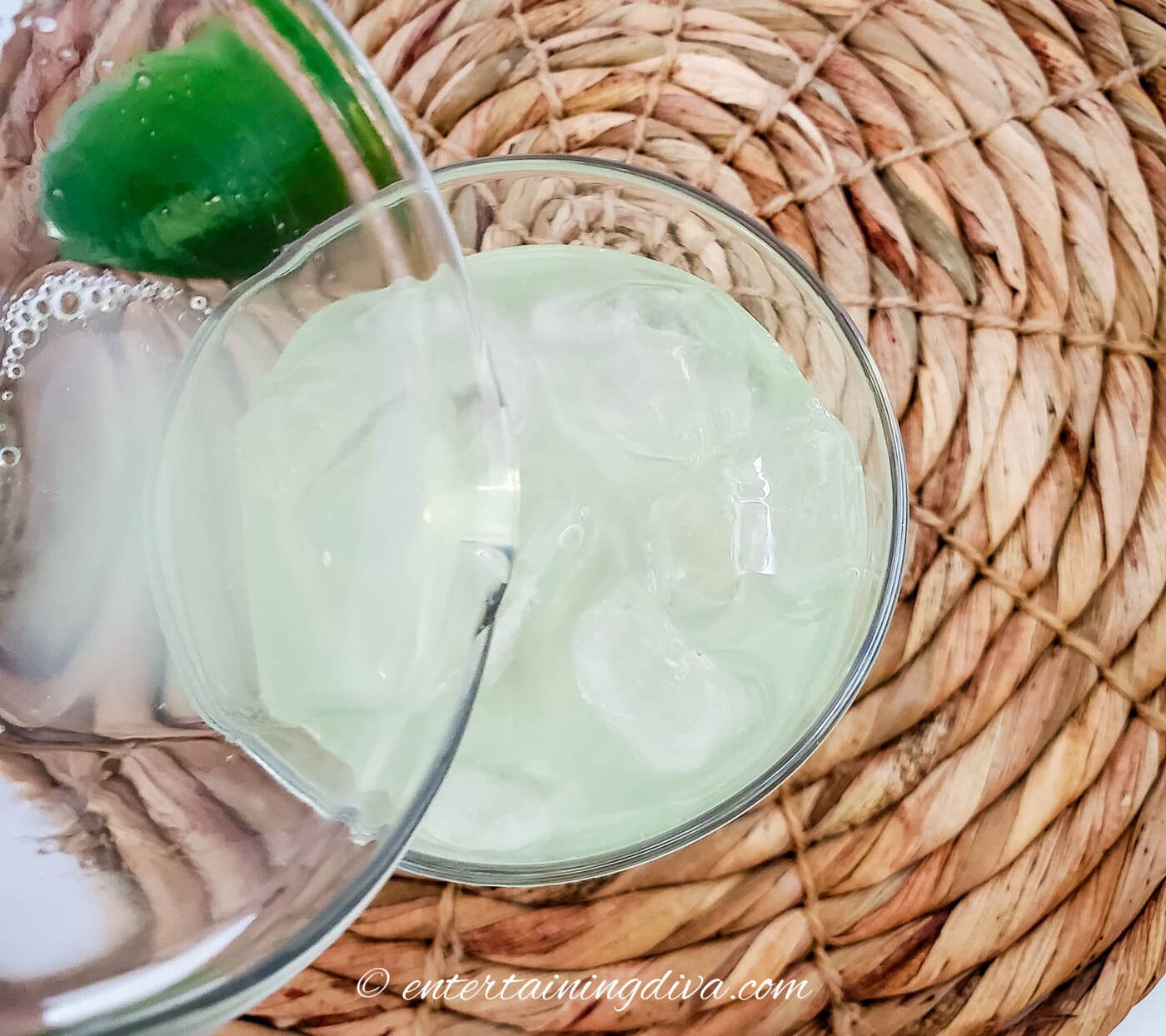 margarita mix being poured into a glass with ice