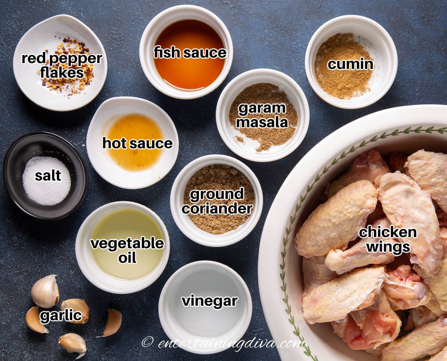 marinated Asian spice chicken wings ingredients - fish sauce, cumin, garam masala, ground coriander, vinegar, vegetable oil, garlic, salt, hot sauce, red pepper flakes