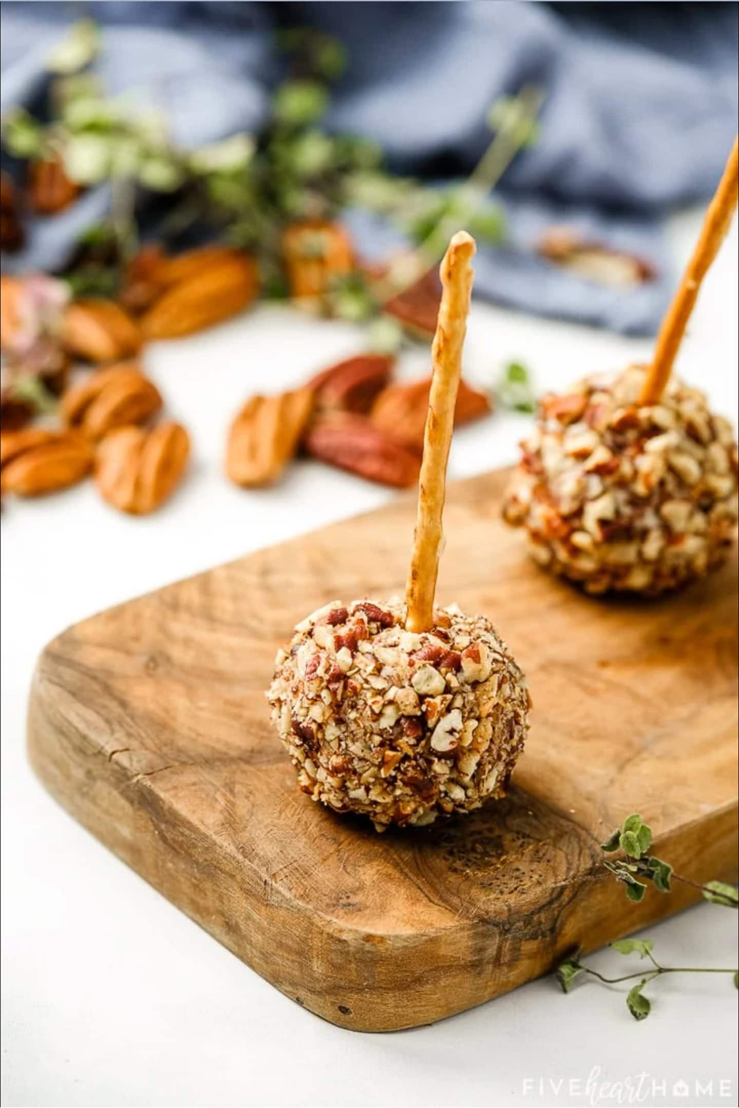 Pecan apple balls on a cutting board with a toothpick.