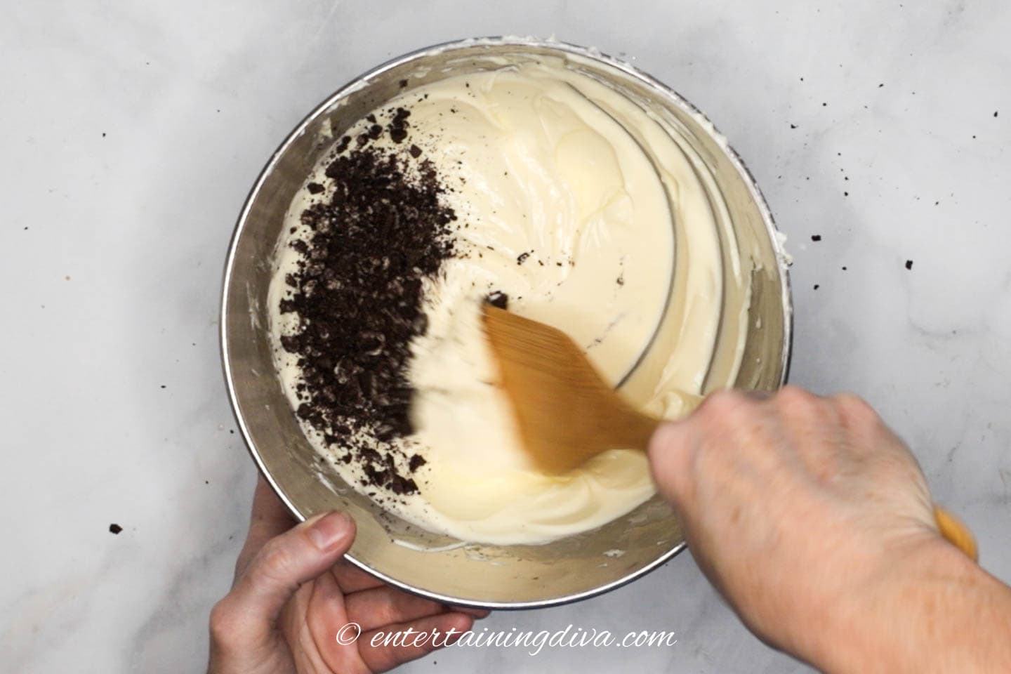 Chopped Oreo cookies being stirred into the cheesecake batter