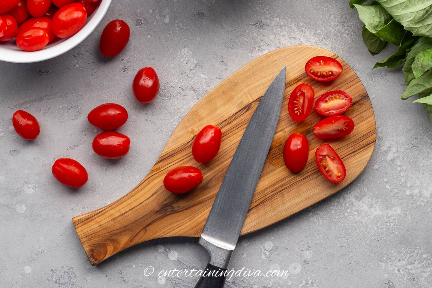 Grape tomatoes on a cutting board with a knife