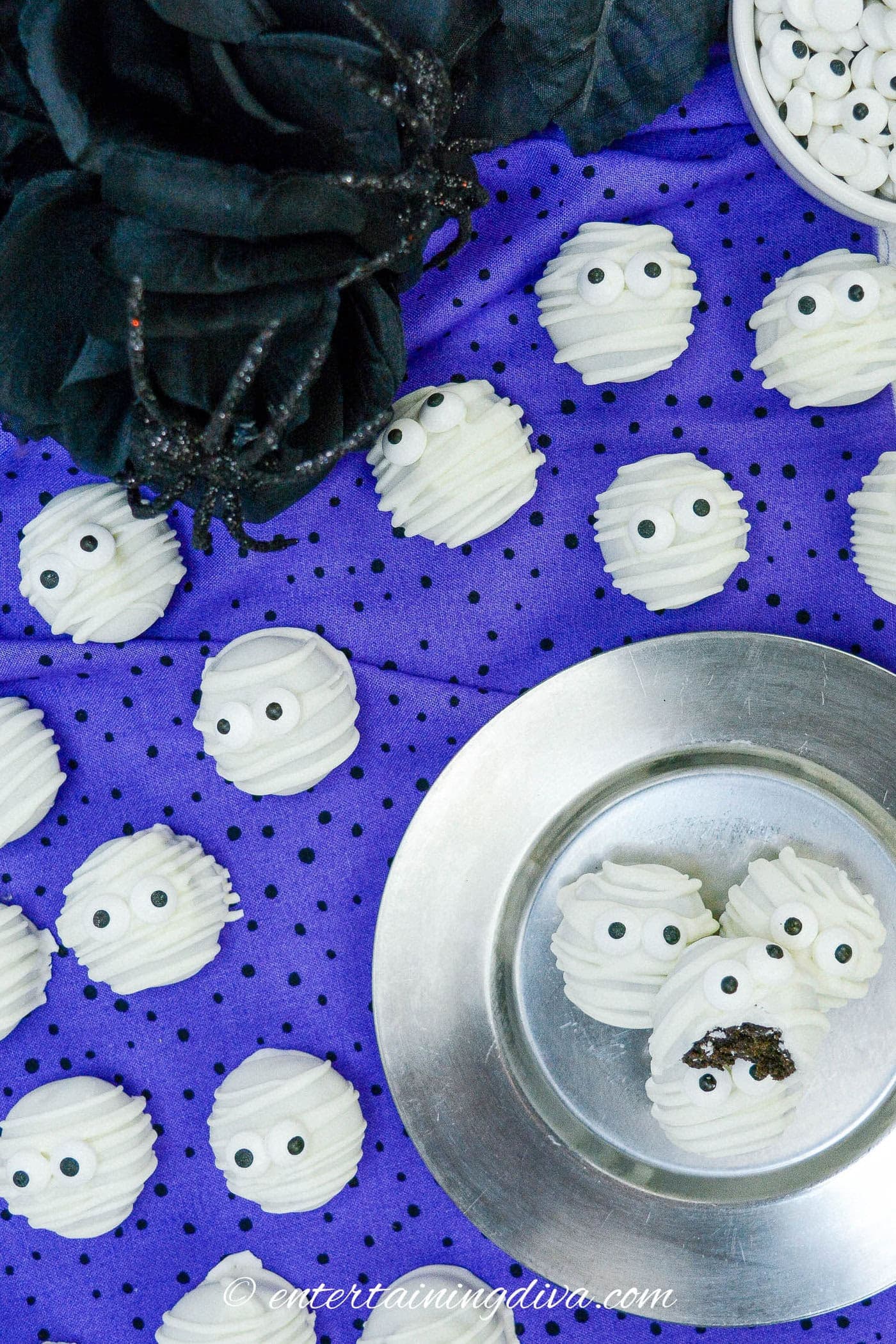 an overhead picture of Halloween mummy Oreo balls on a purple background with fake spiders