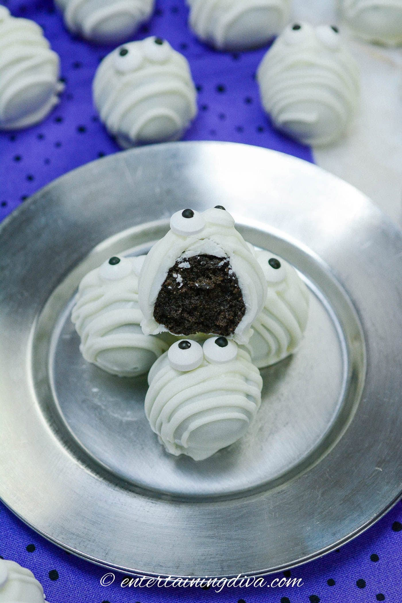 a stack of mummy Oreo balls on a plate with a bite out of one
