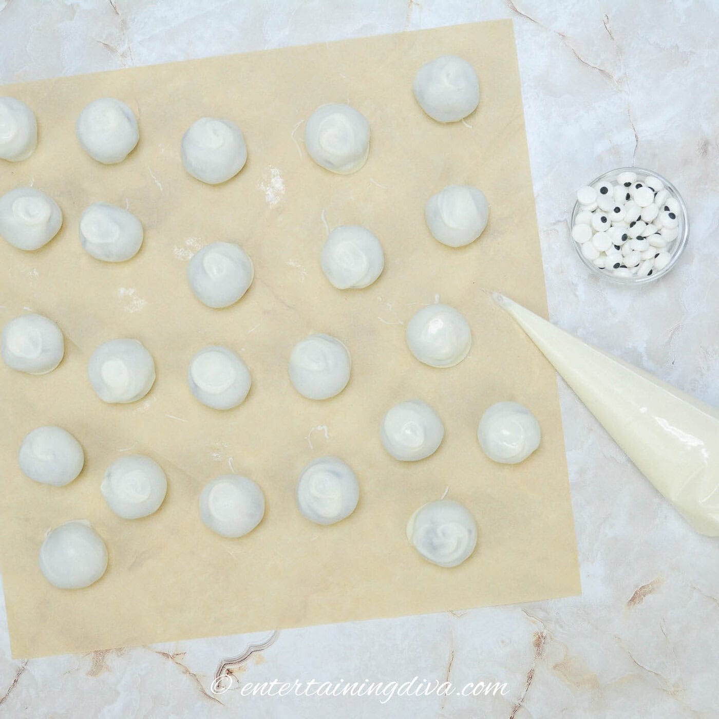 Oreo balls covered with white chocolate beside a piping bag filled with white chocolate