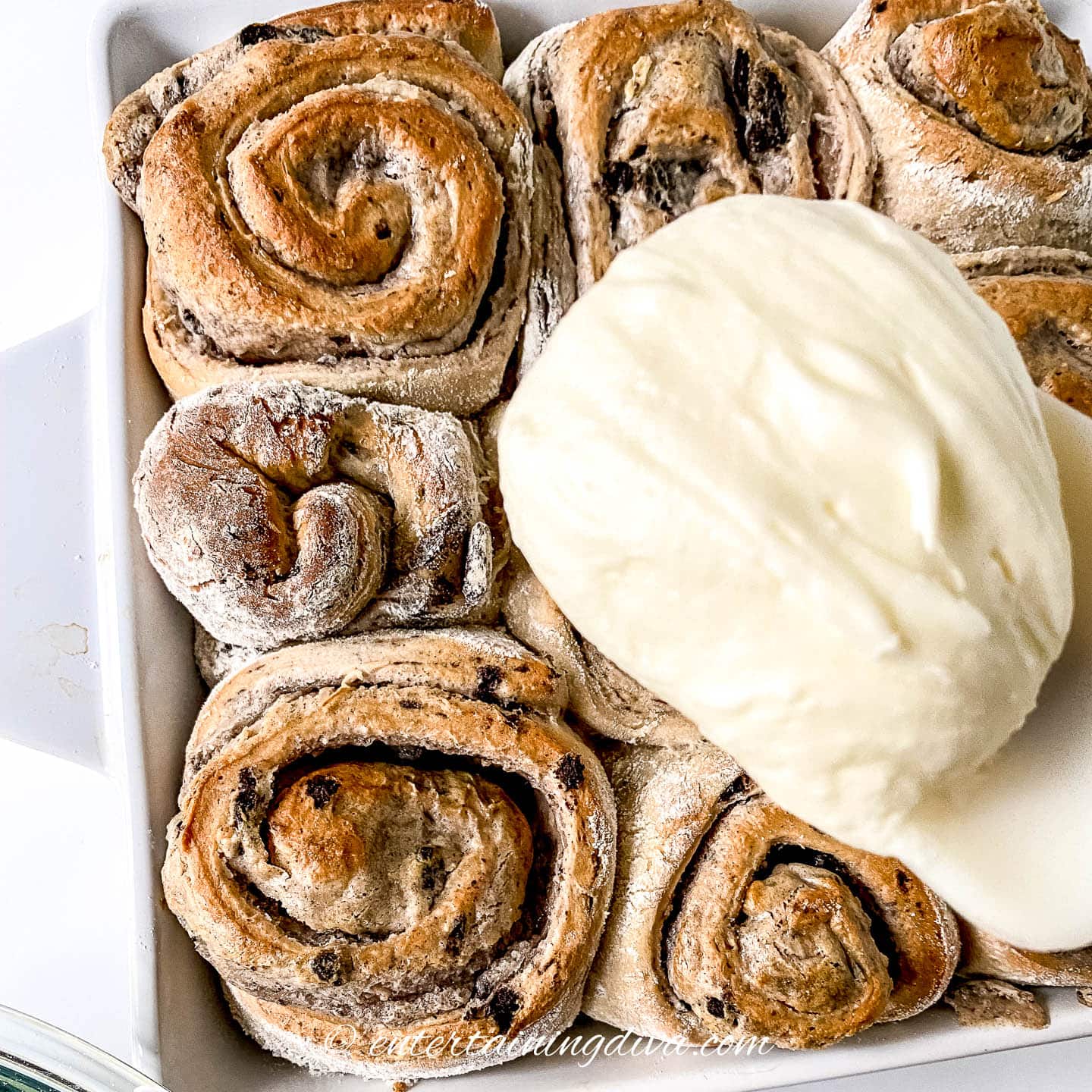 a pan of Oreo cinnamon rolls with a dollop of glaze on top