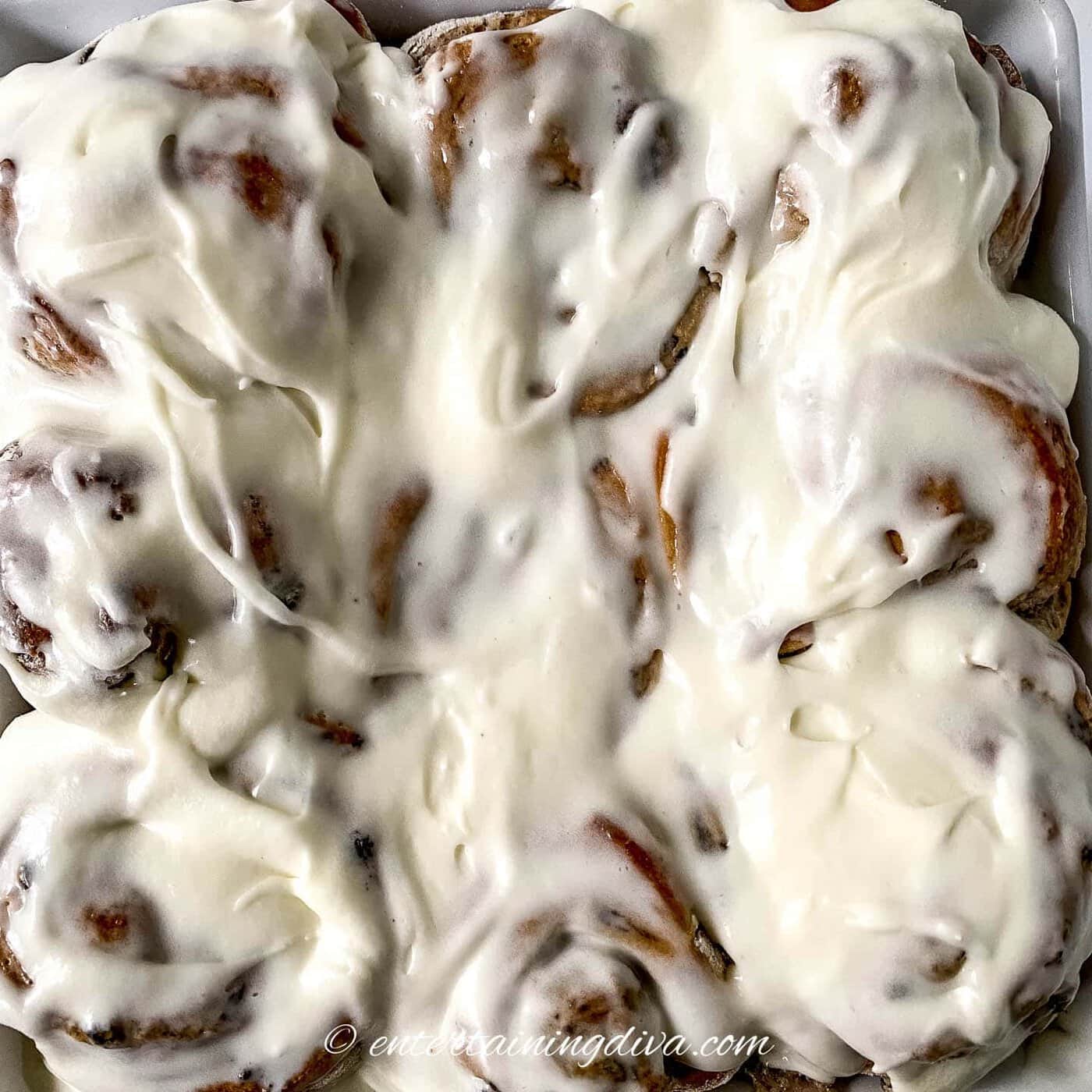 a pan of cinnamon rolls with glaze on top
