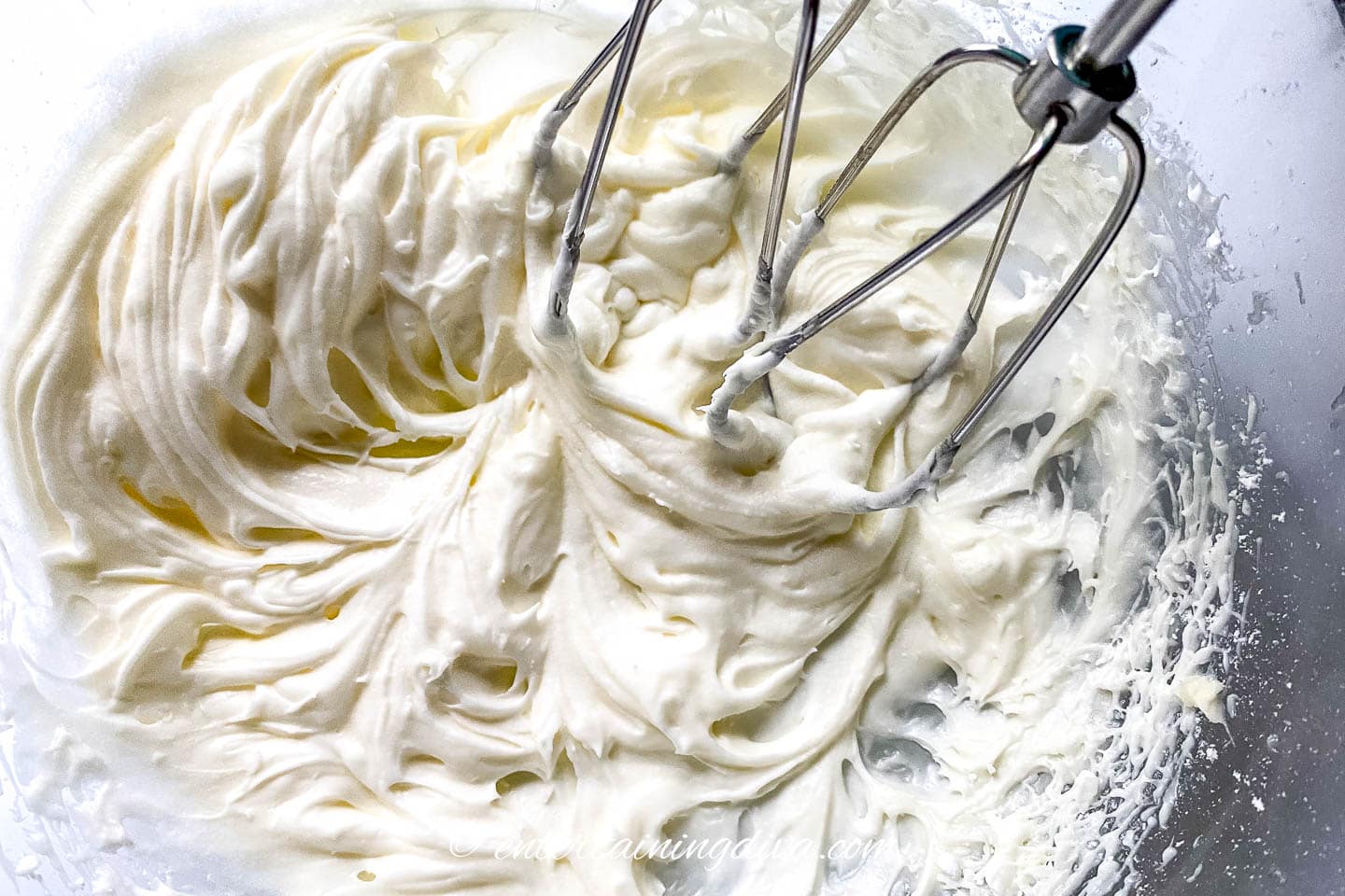 oreo cinnamon roll glaze with mixer in a bowl