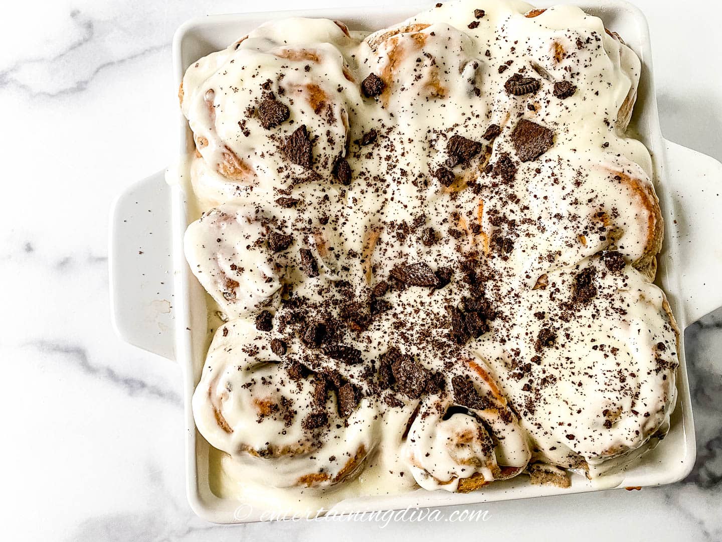 Oreo cinnamon rolls in a baking dish with Oreos and vanilla glaze on top