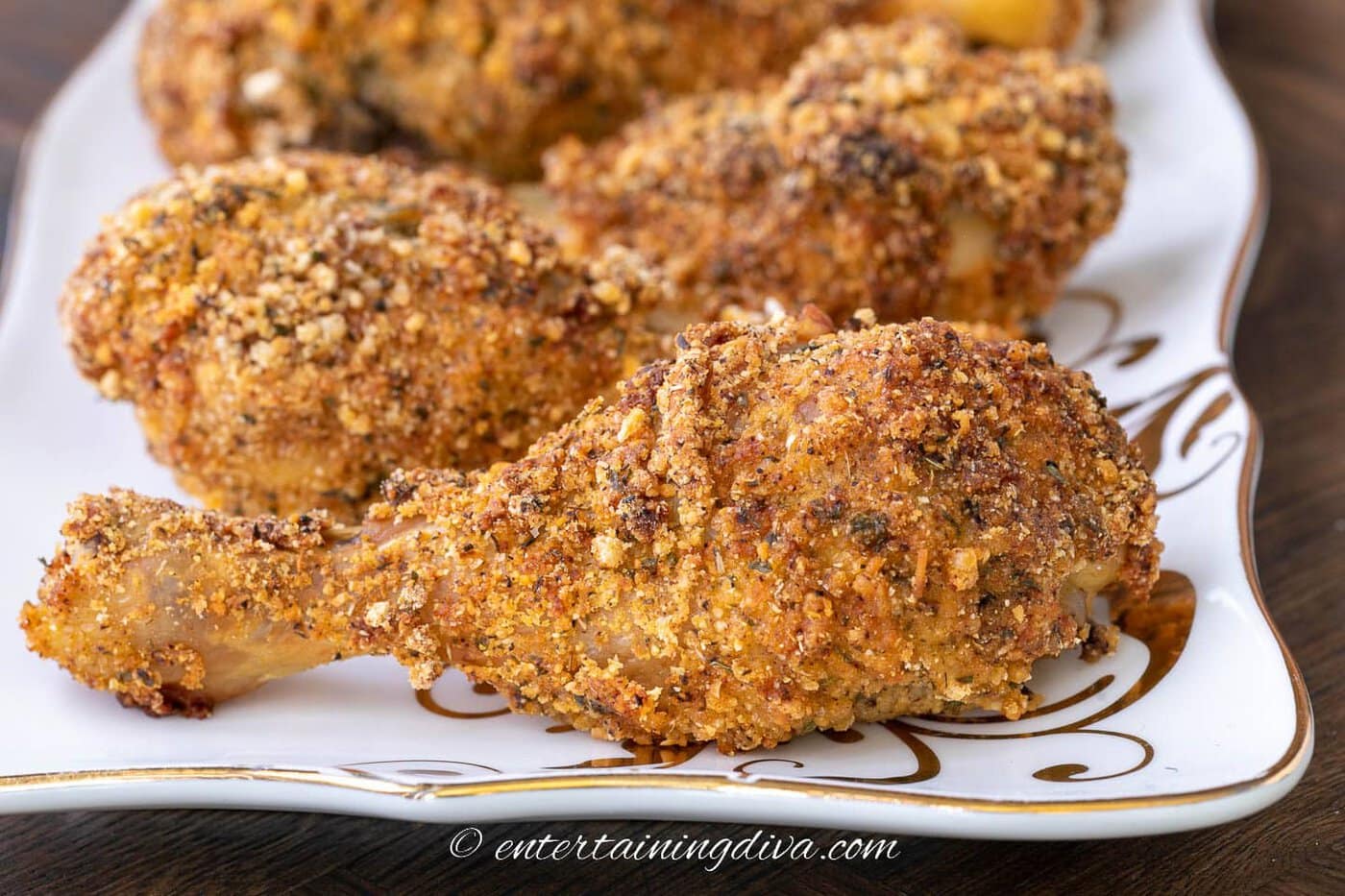a row of baked breaded chicken legs on a tray