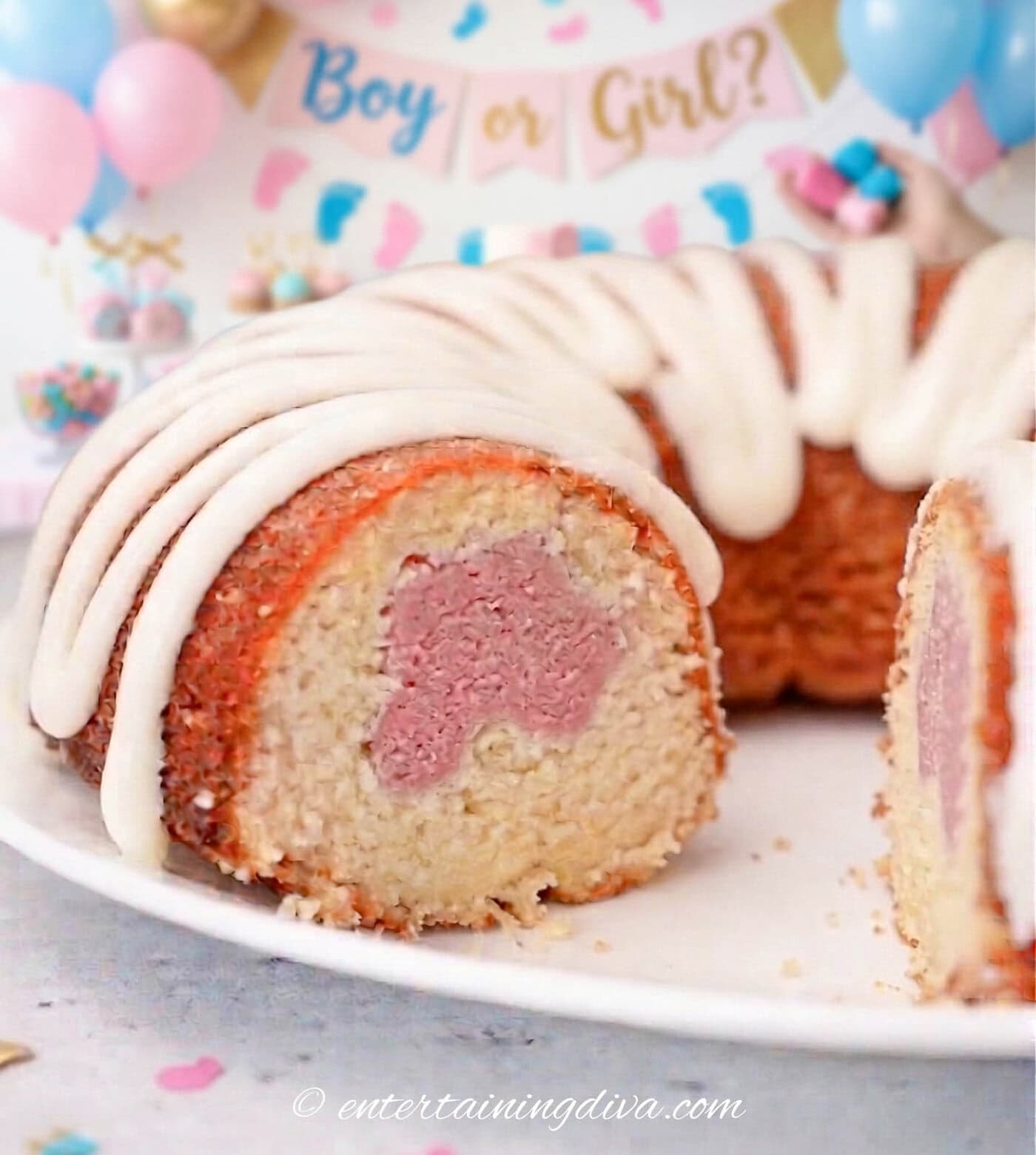a pastel swirl bundt cake with pink in the middle and white icing for a gender reveal party