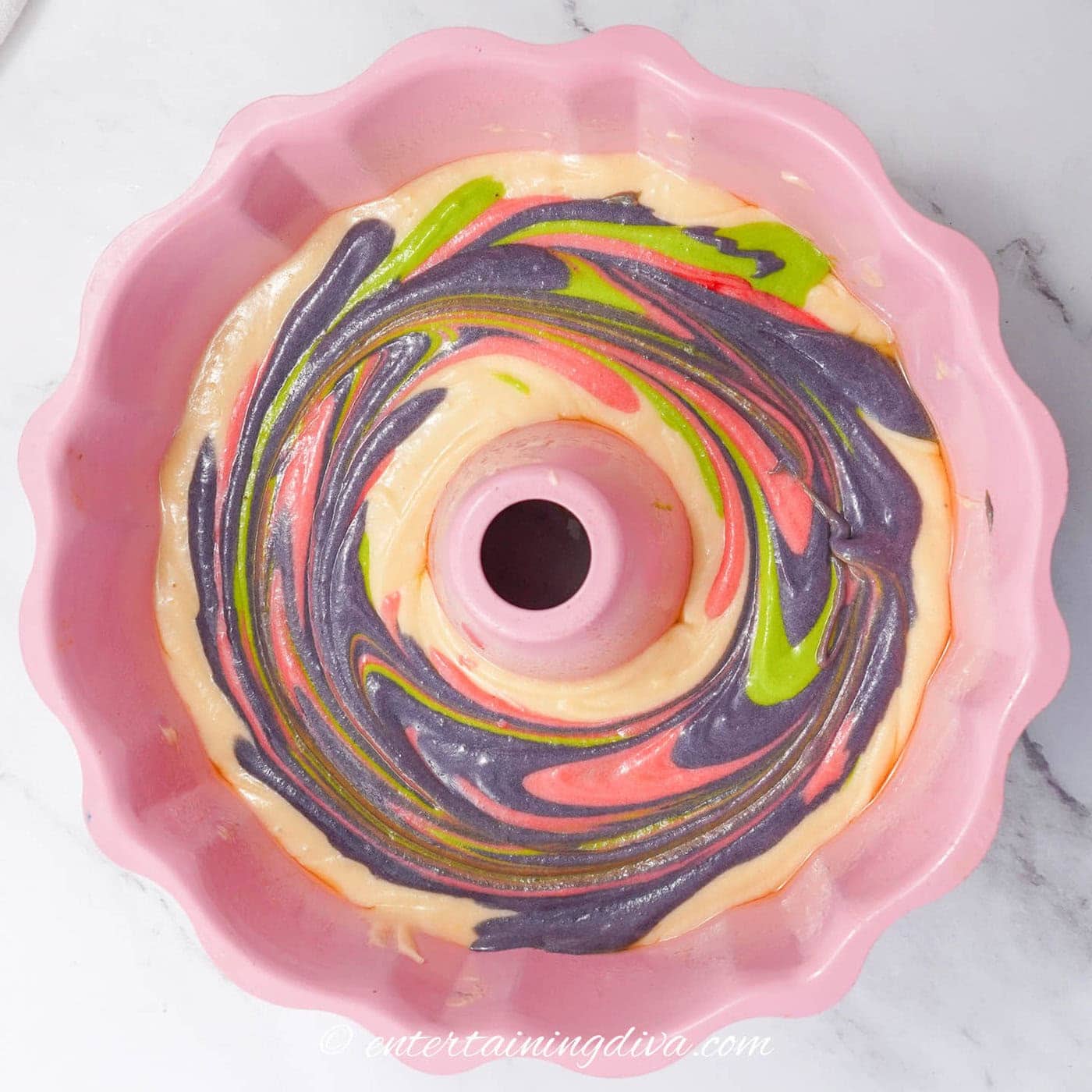 pink, purple and green batter swirled in a bundt cake pan