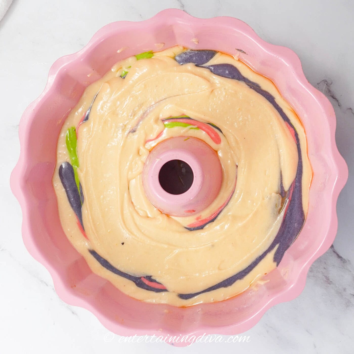 pound cake batter spread over the top of swirled colored batter