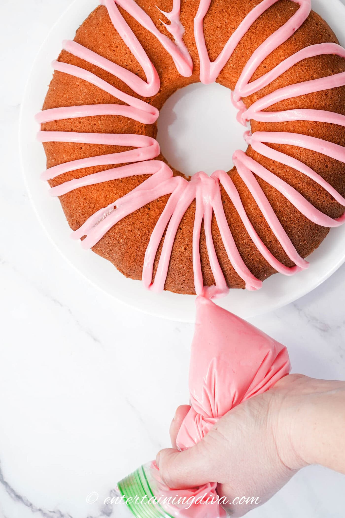 pink icing being drizzled onto the top of a bundt cake