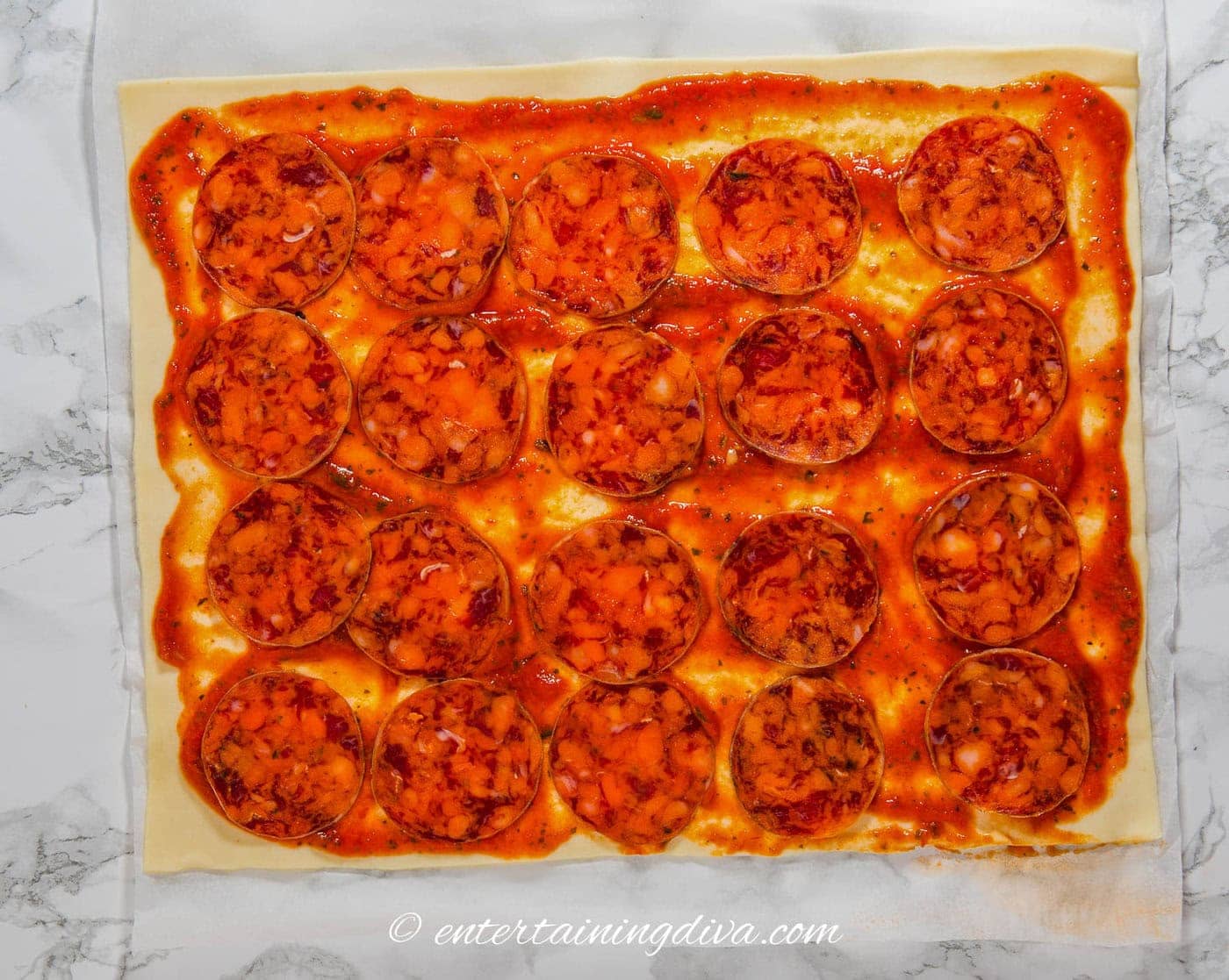 pepperoni spread out over tomato sauce on phyllo dough