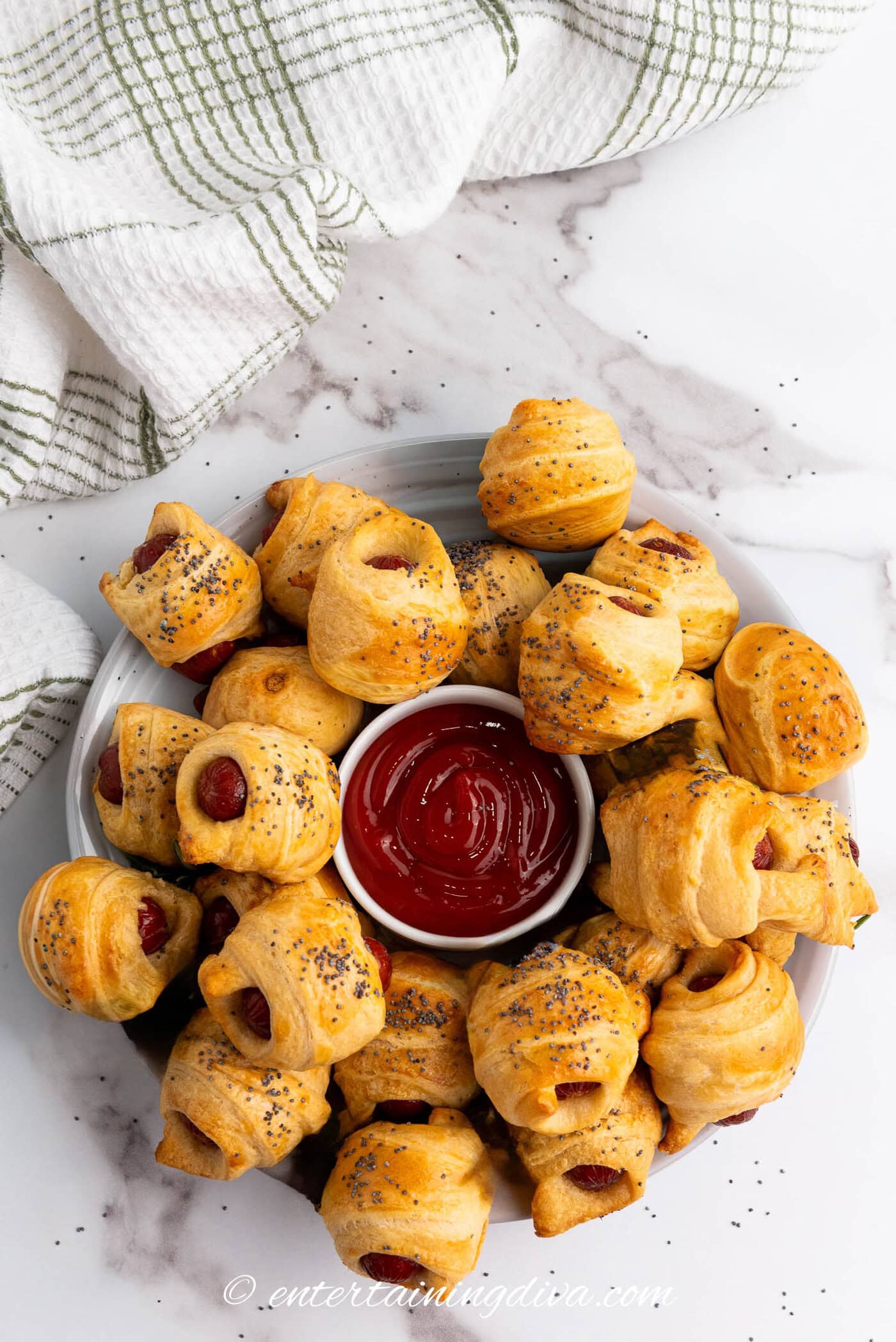 overhead of pigs in a blanket on a plate with a bowl of ketchup in the middle