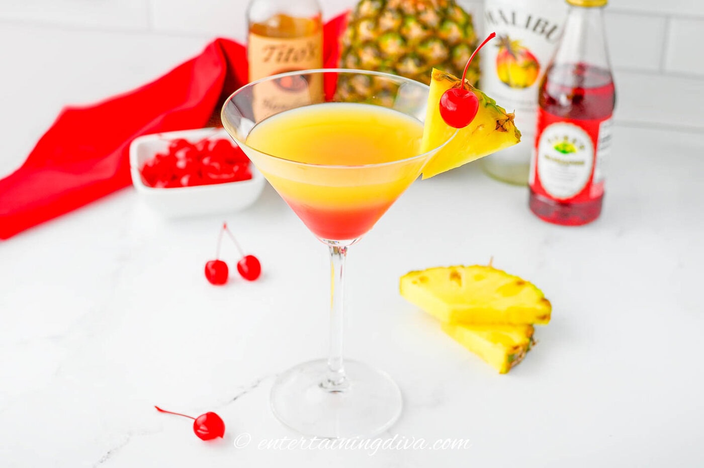 A pineapple upside down cake martini garnished with a pineapple slice and a marashino cherry
