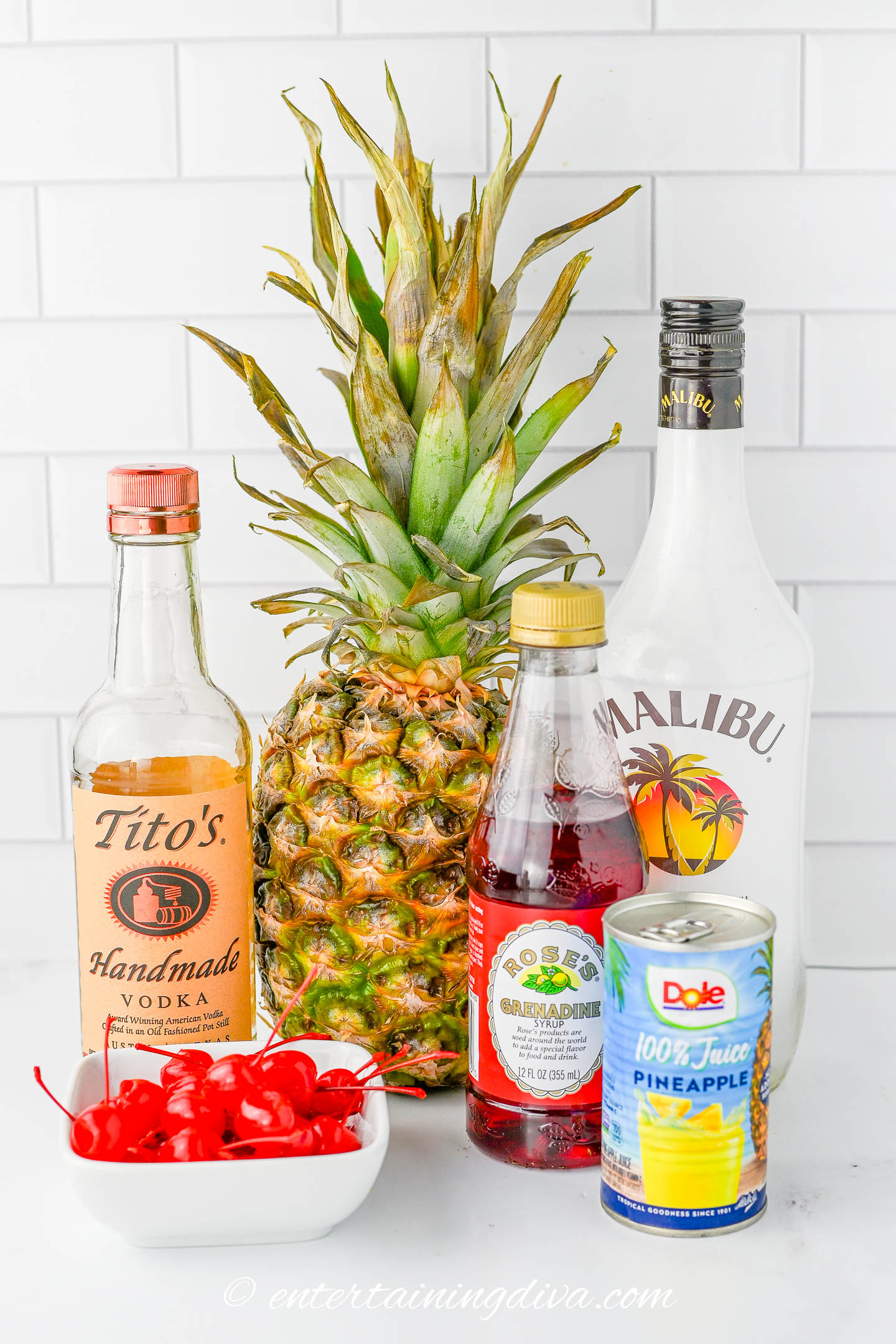ingredients for pineapple upside down cake drink recipe - vodka, Malibu rum, pineapple juice, grenadine, fresh pineapple and maraschino cherries