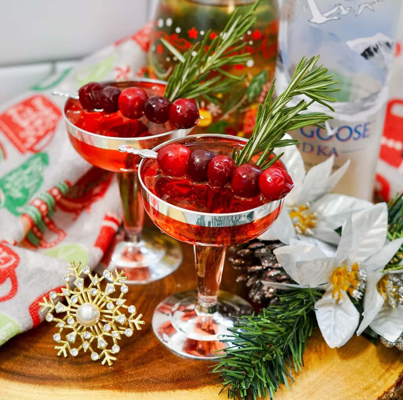 Two martini glasses with cranberries and sprigs of rosemary.