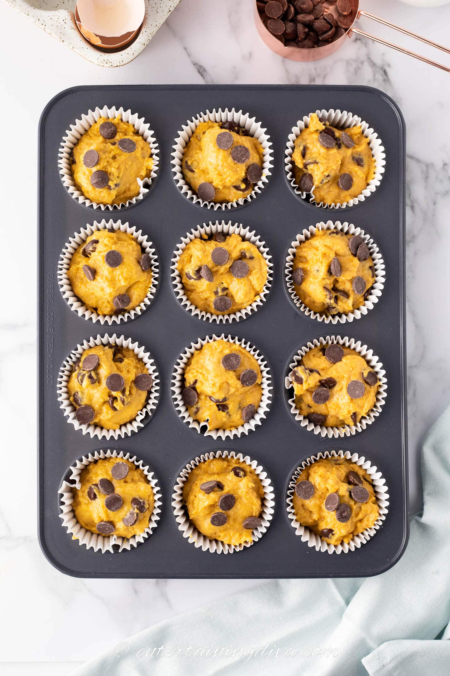 pumpkin chocolate chip muffins in a muffin tin before baking