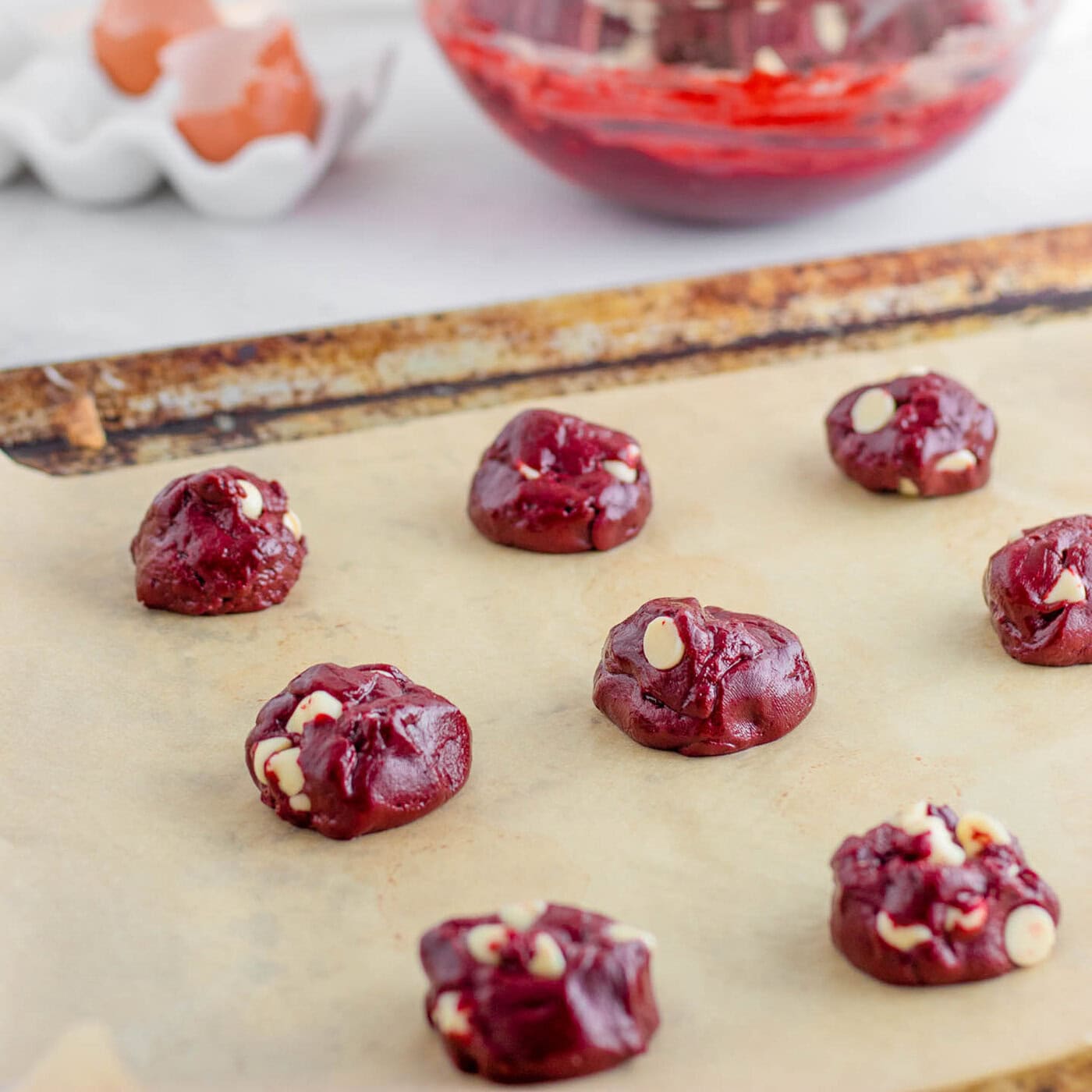 scoops of red velvet cake mix with white chocolate chips on a baking sheet