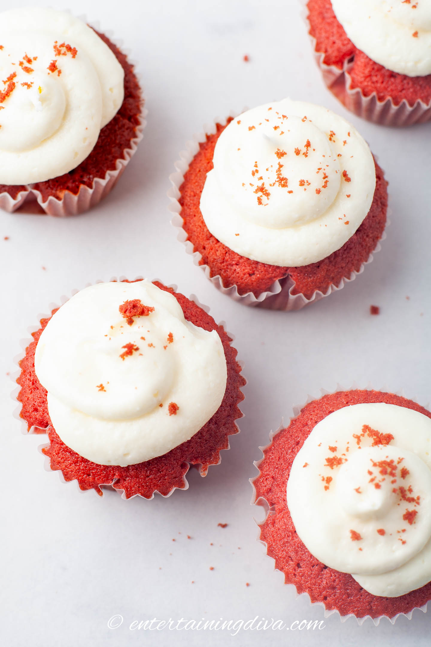 overhead picture of red velvet cupcakes with cream cheese frosting and red sprinkles