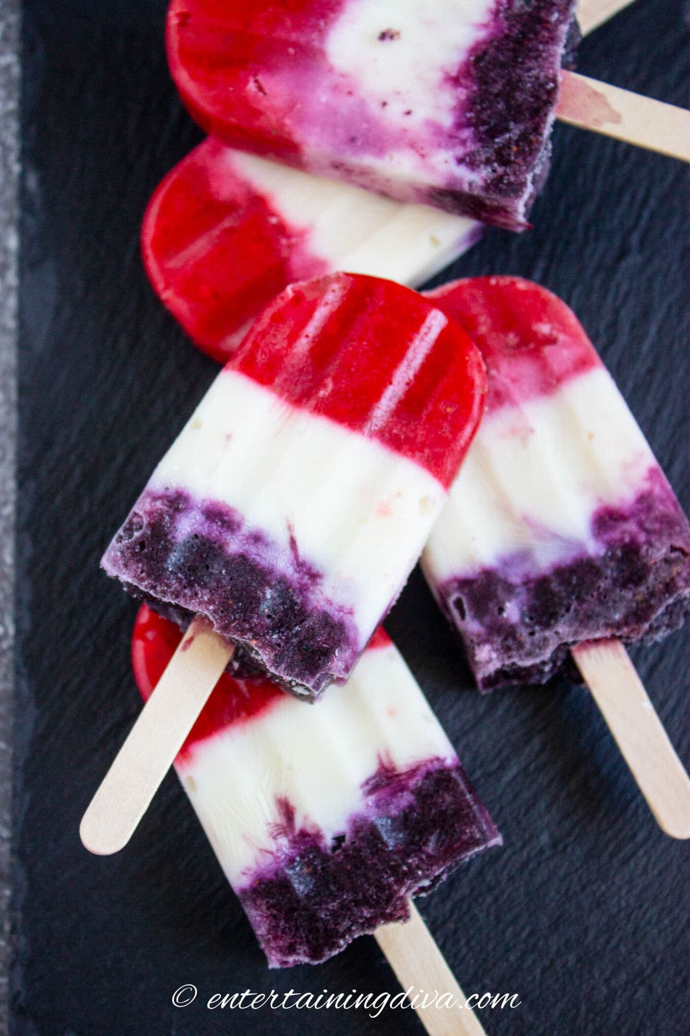 5 red white and blue popsicles on a dark countertop