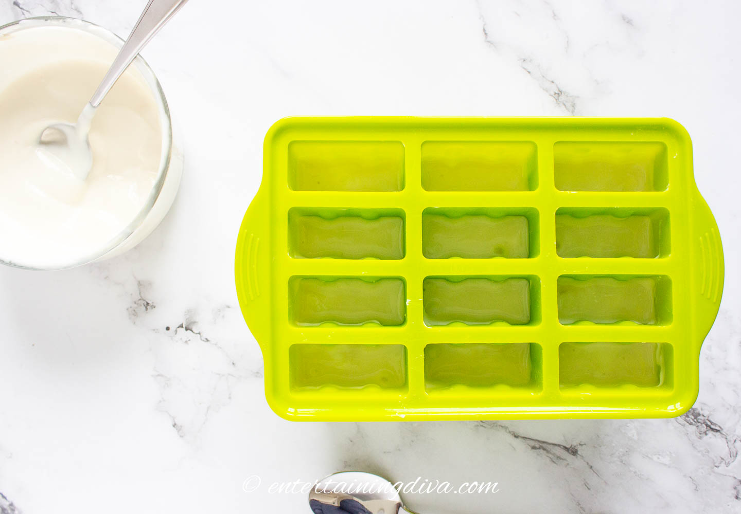 a bowl of yogurt beside a popsicle mold that is 2/3 full