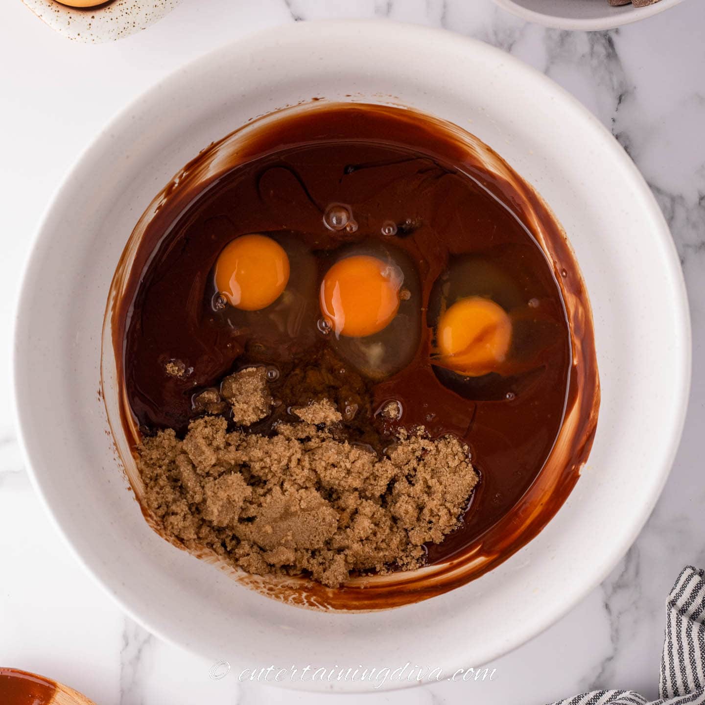 Melted chocolate, eggs, brown sugar and vanilla extract in a bowl.