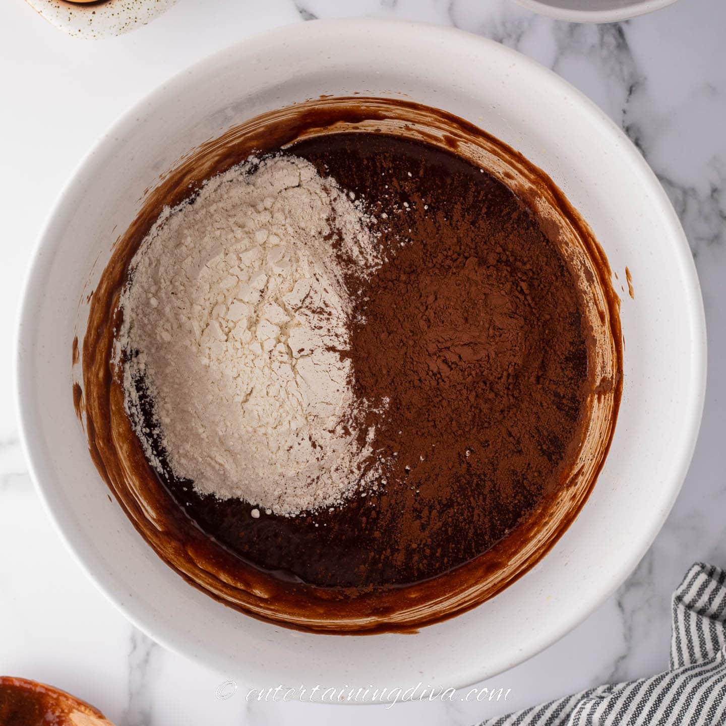 Flour and cocoa powder added to the melted chocolate in a bowl