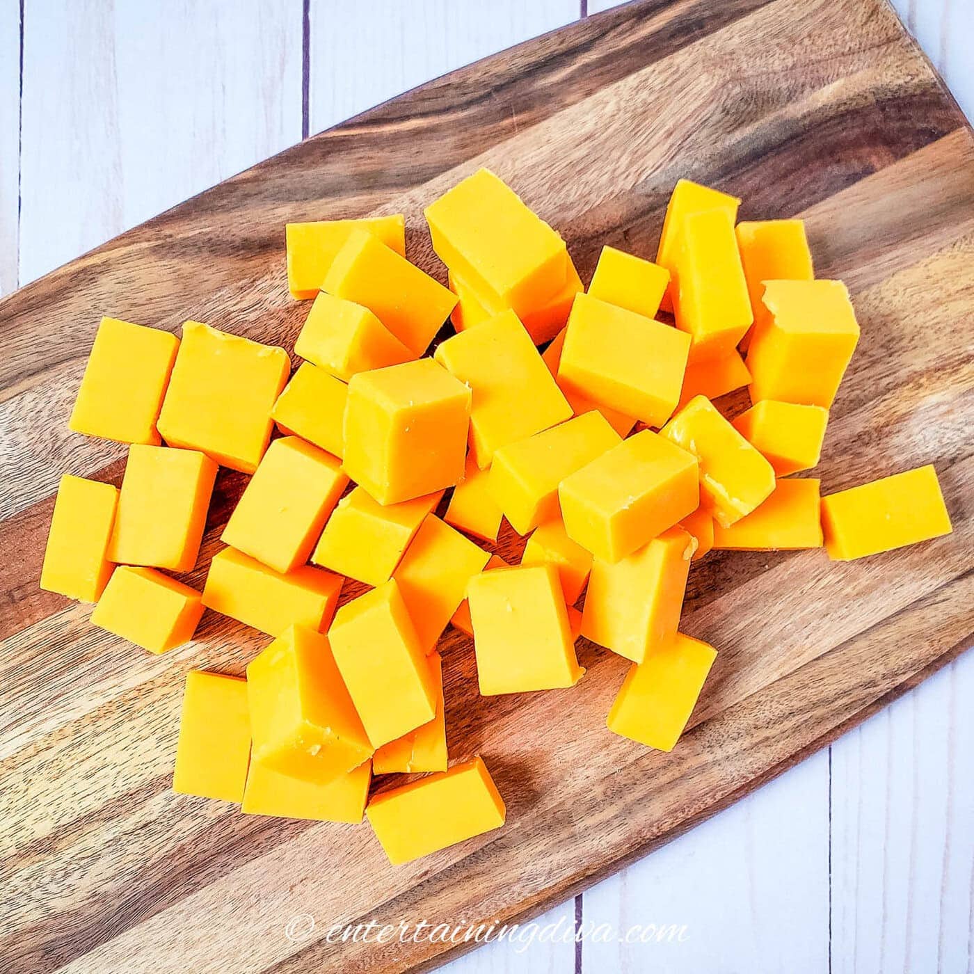 cubed cheddar cheese on a cutting board