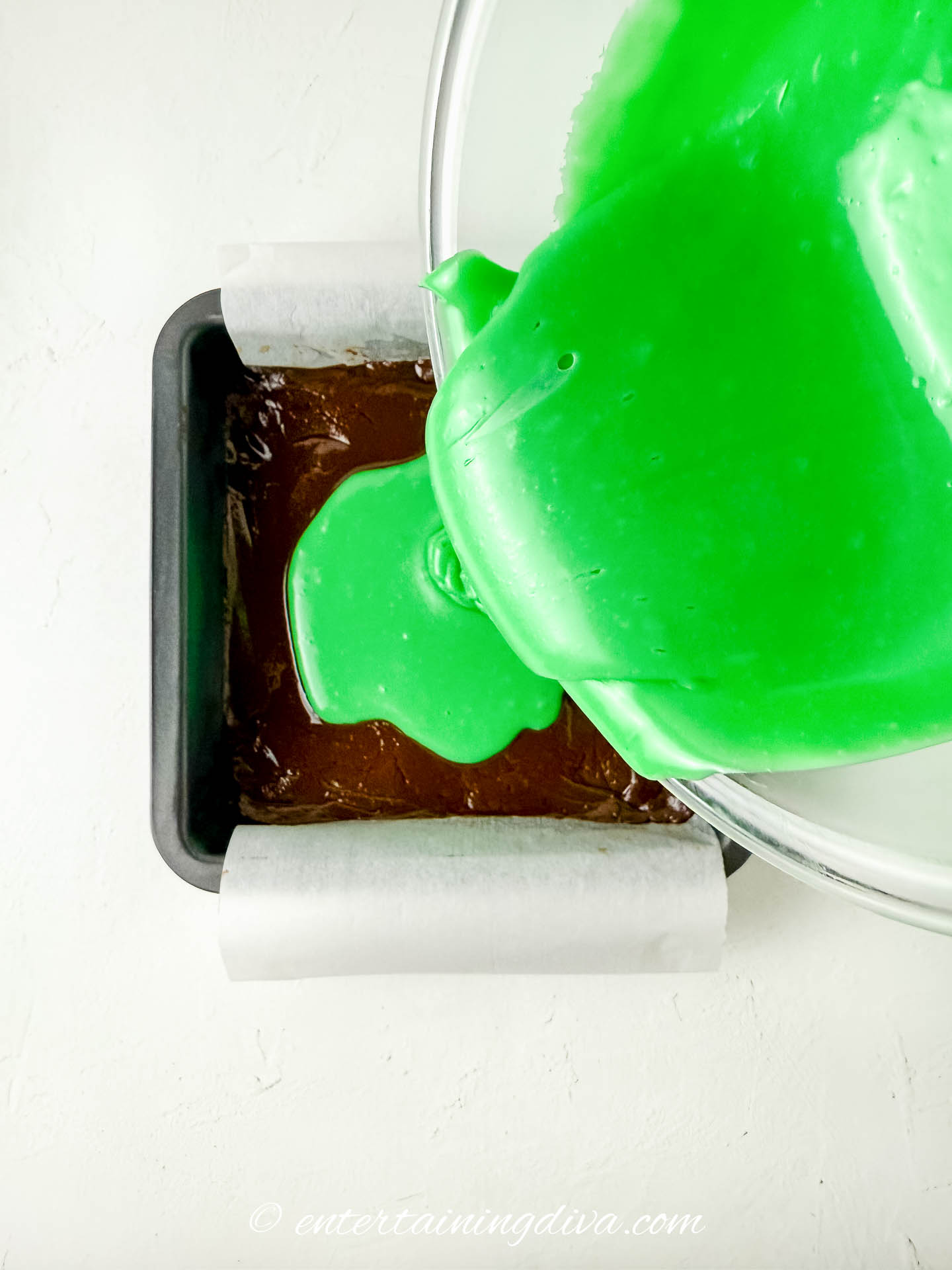 green fudge being poured on top of chocolate fudge