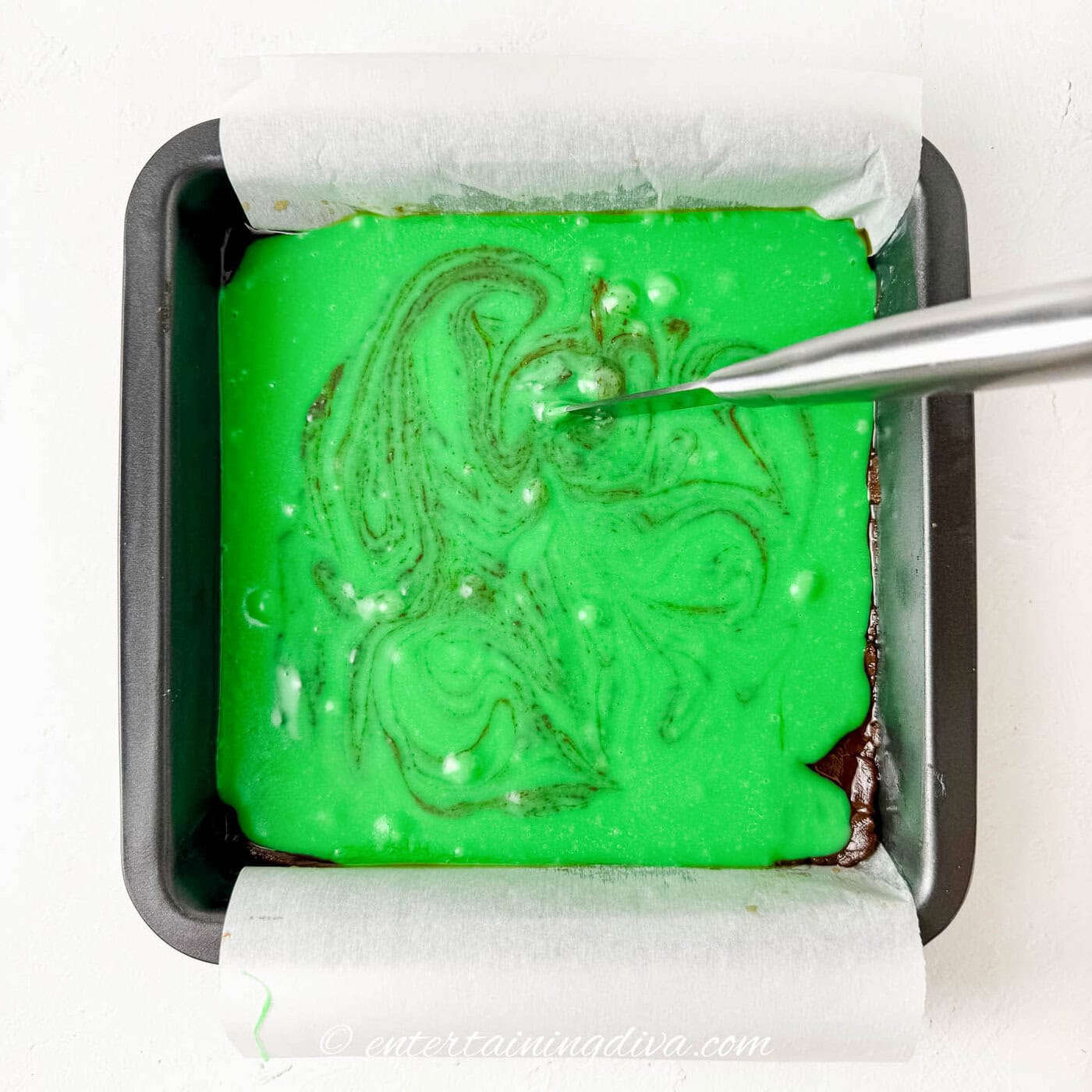A knife making swirls in the green fudge
